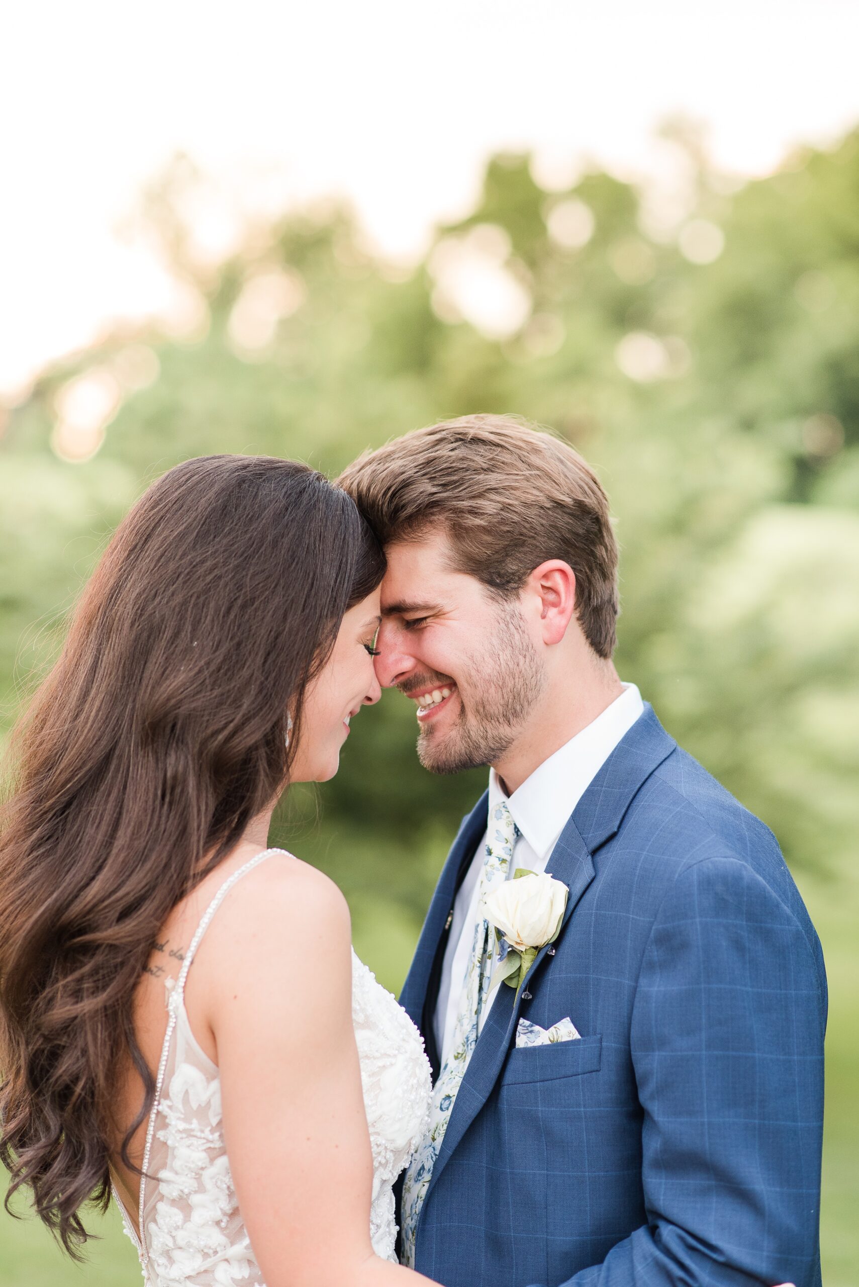 Newlyweds giggle while standing forehead to forehead