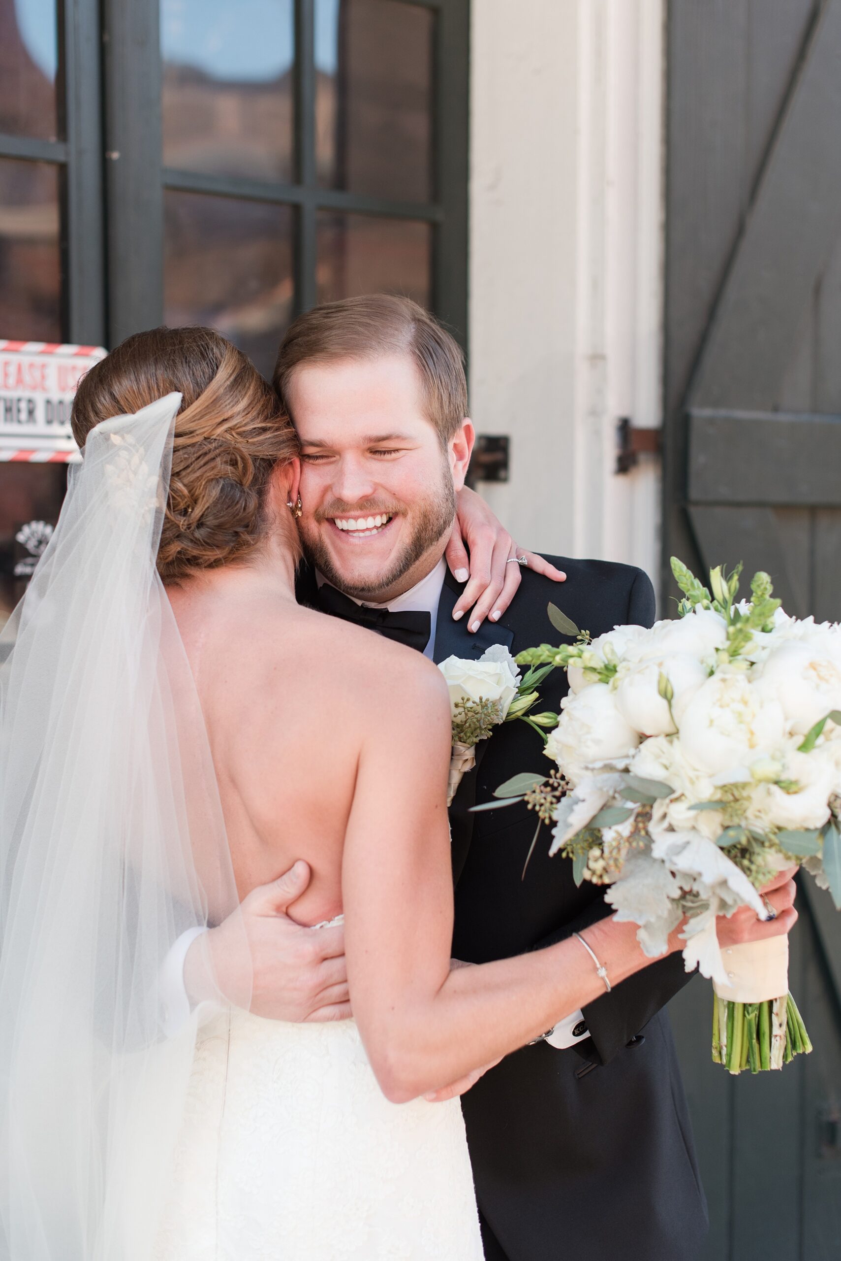 Newlyweds laugh and hug while standing on the street