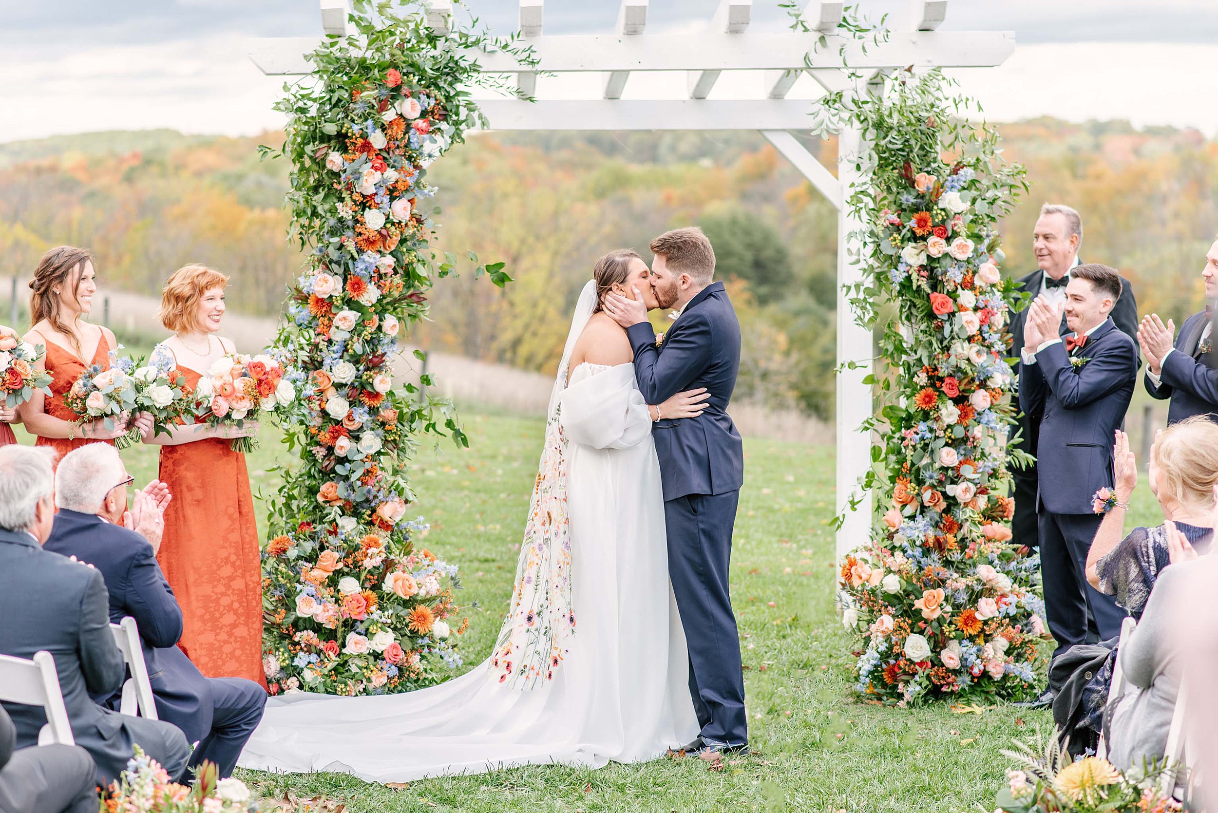 Newlyweds kiss to end their ceremony under a white pergola on a hill at one of the Annapolis Wedding Venues
