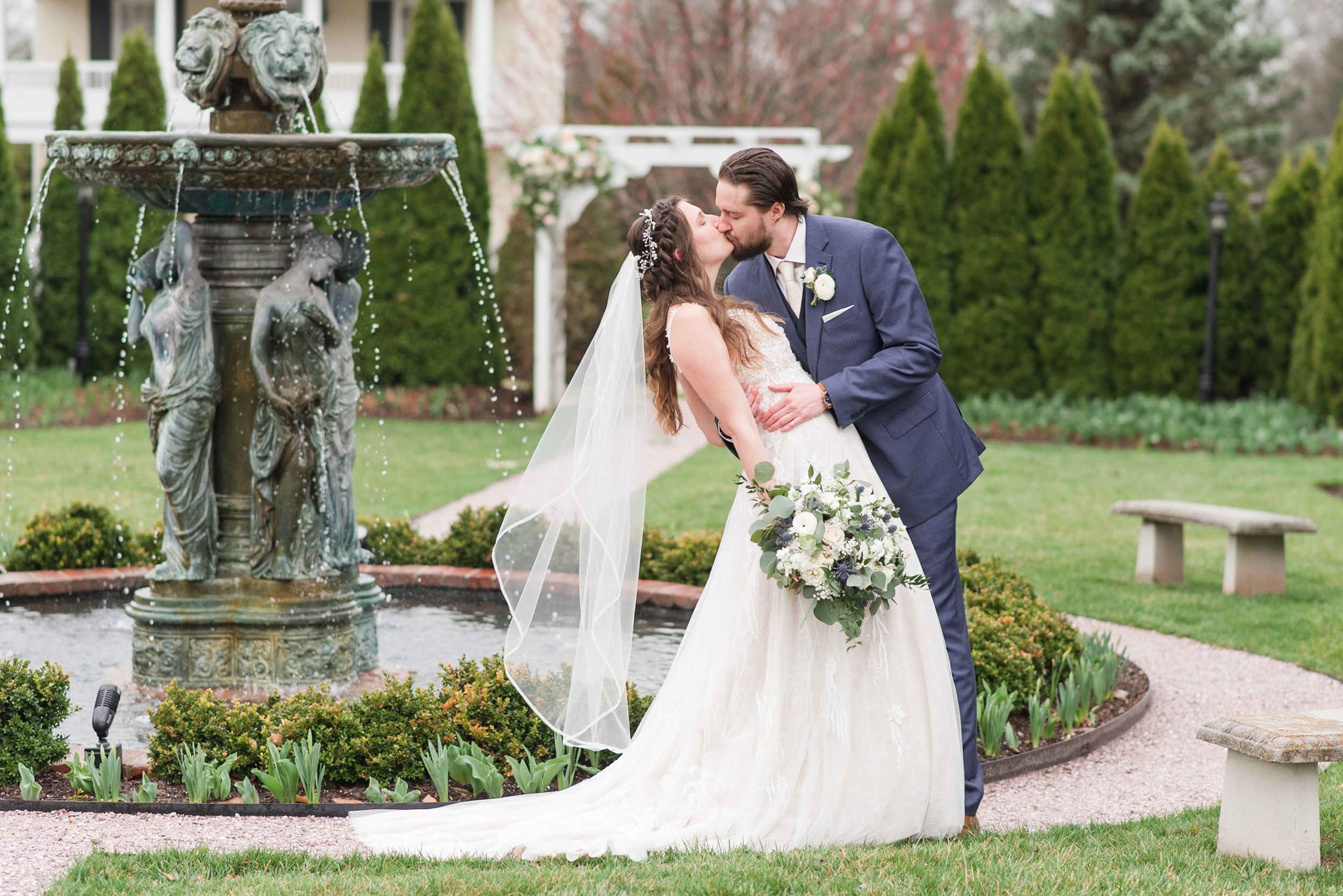 Newlyweds kiss in the gardens by the fountains at their Antrim 1844 Wedding
