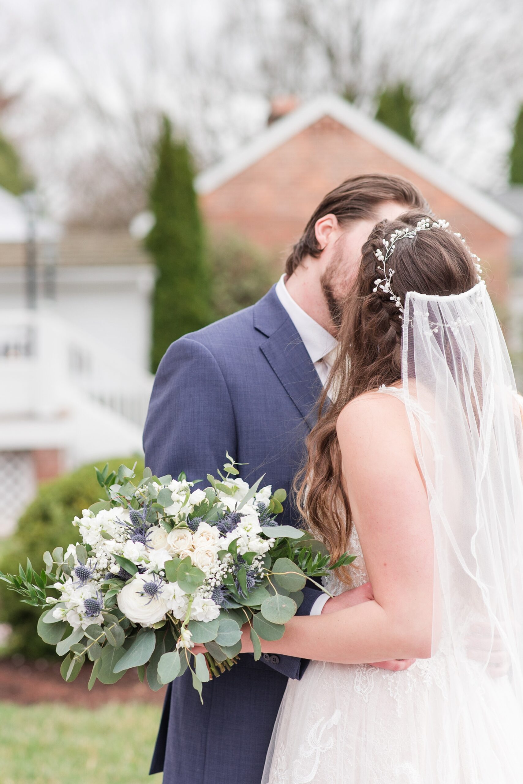 Newlyweds kiss while holding a unique bouquet in a lawn