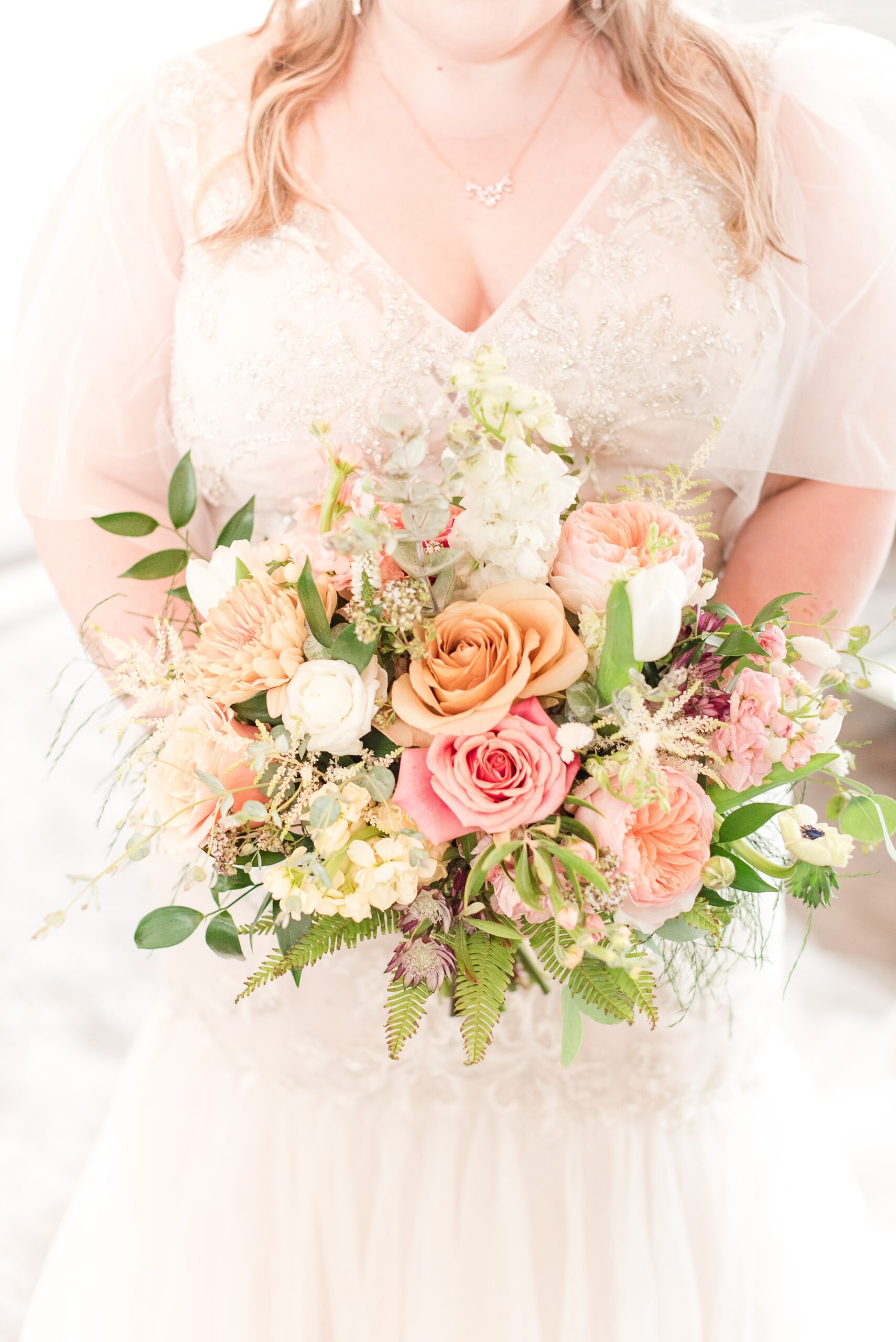 A bride stands holding her colorful pink and orange bouquet at her Appleford Estate Wedding