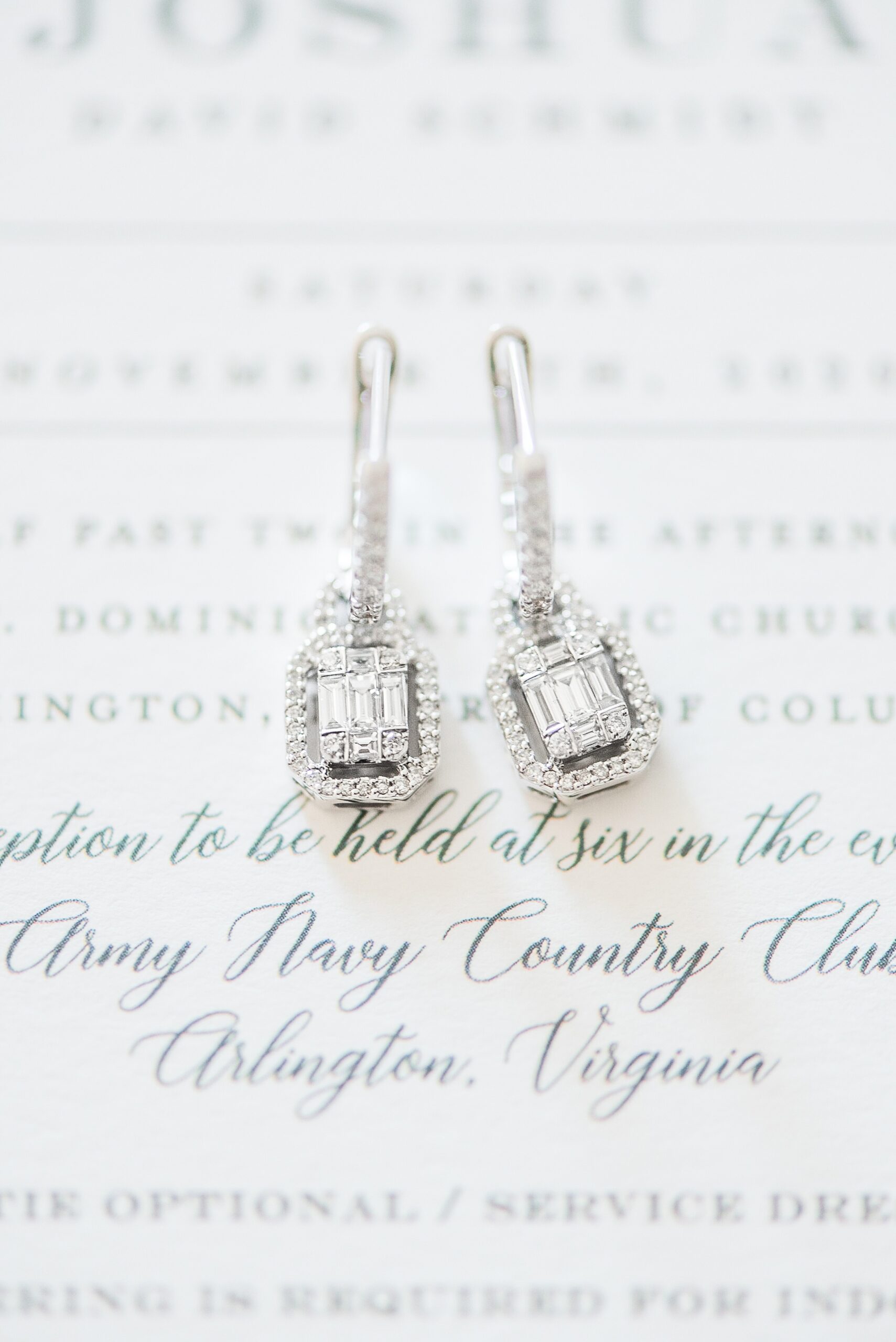 Details of diamond wedding earrings sitting on an invitation for an Army Navy Club Wedding