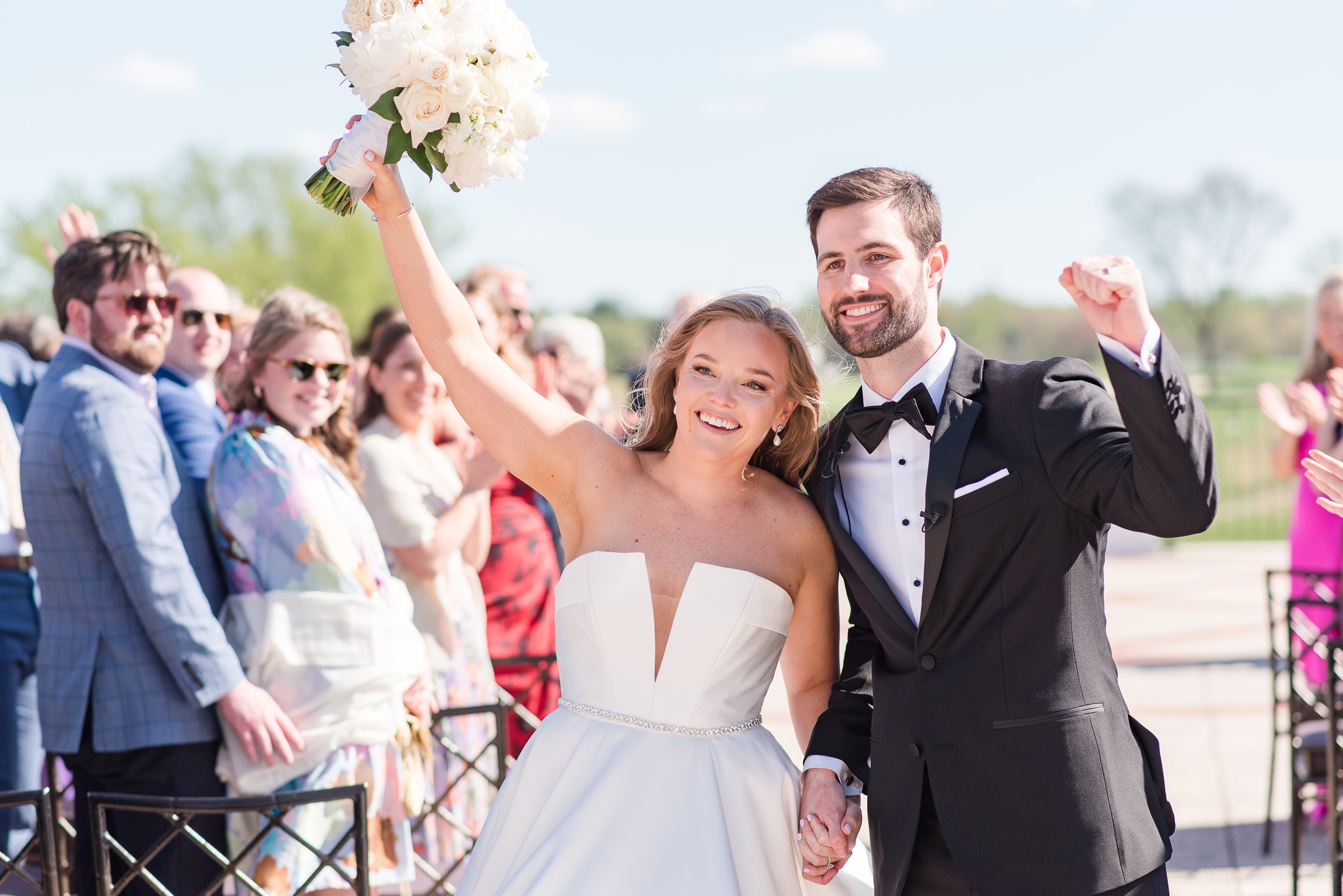 Newlyweds put their hands in the air while exiting their wedding ceremony