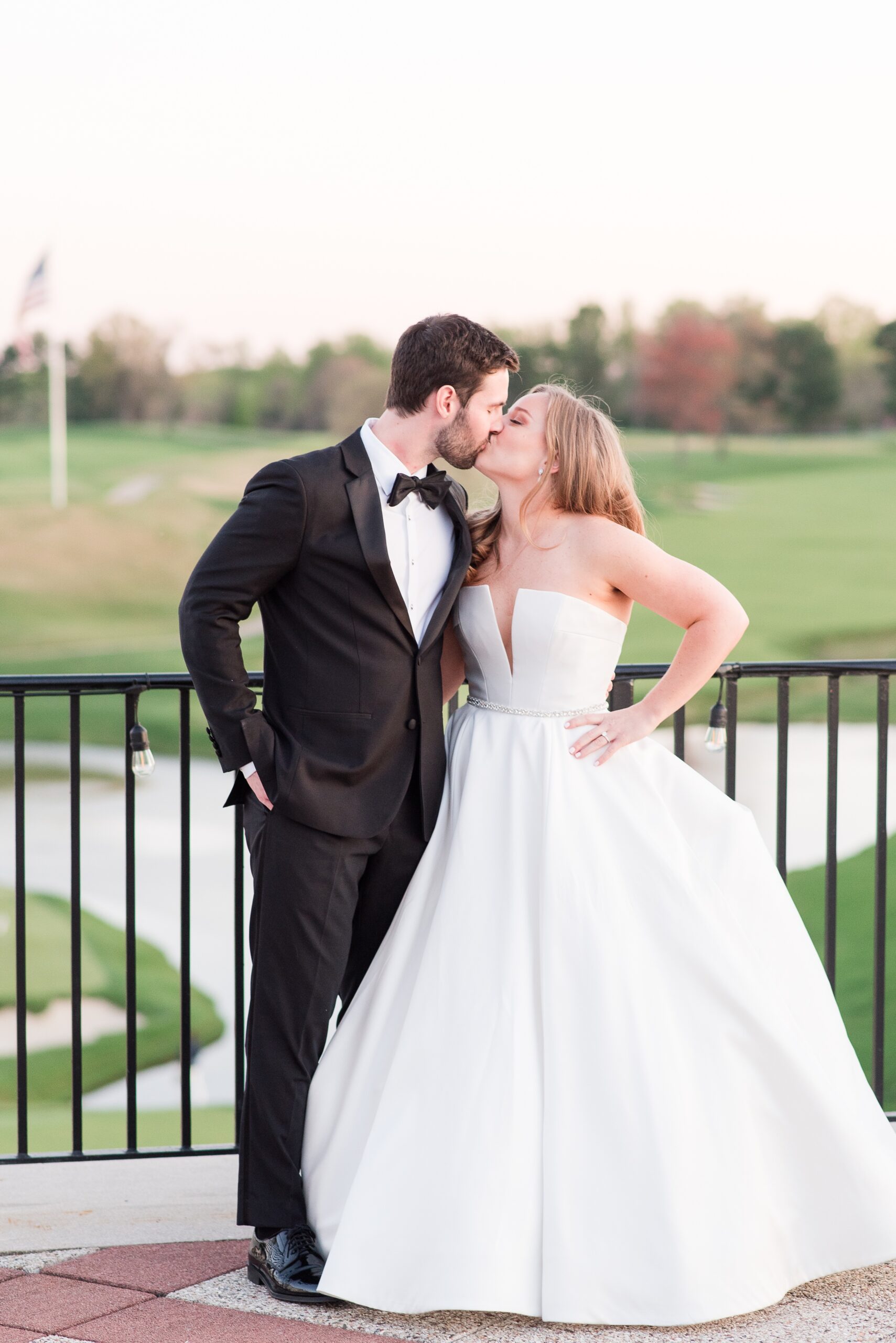 Newlyweds kiss while overlooking the golf course at their Congressional Country Club Wedding