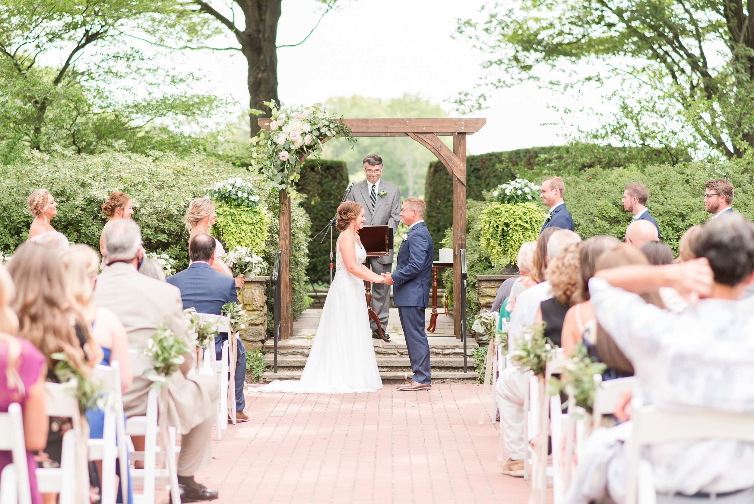 Newlyweds hold hands while standing at the garden altar during their Drumore Estate Wedding