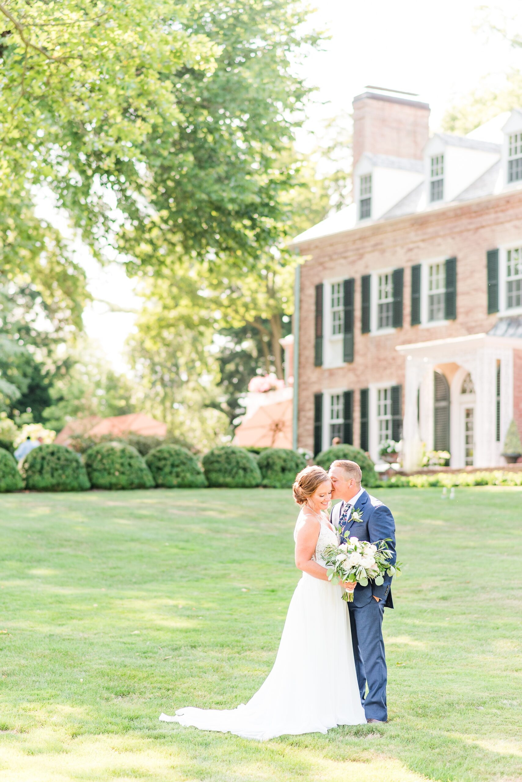 Newlyweds kiss while standing in the lawn at their Drumore Estate Wedding