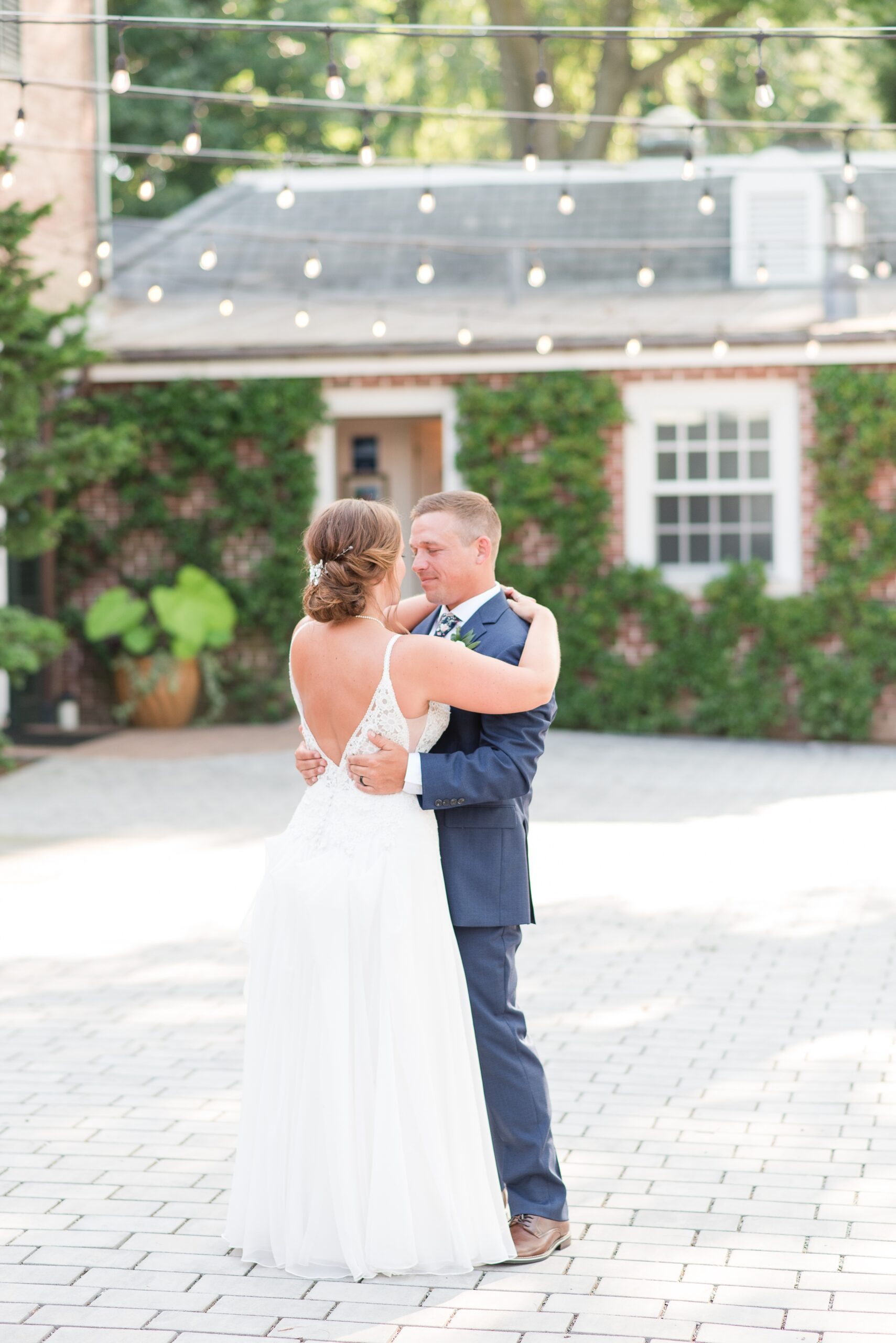 Newlyweds dance alone on a patio under market lights at their Drumore Estate Wedding