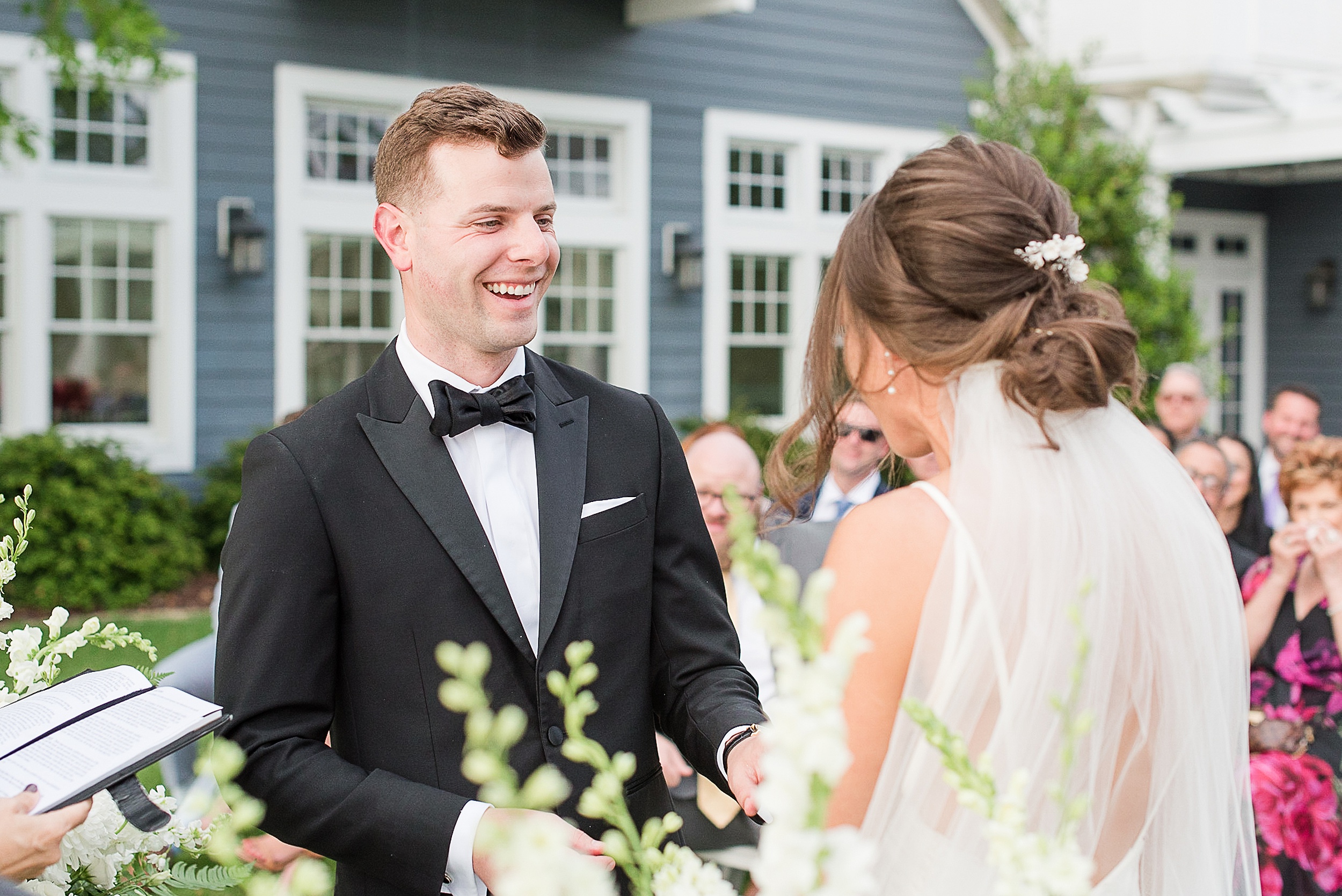 A bride and groom laugh while holding hands during their wedding ceremony at one of the Frederick Wedding Venues