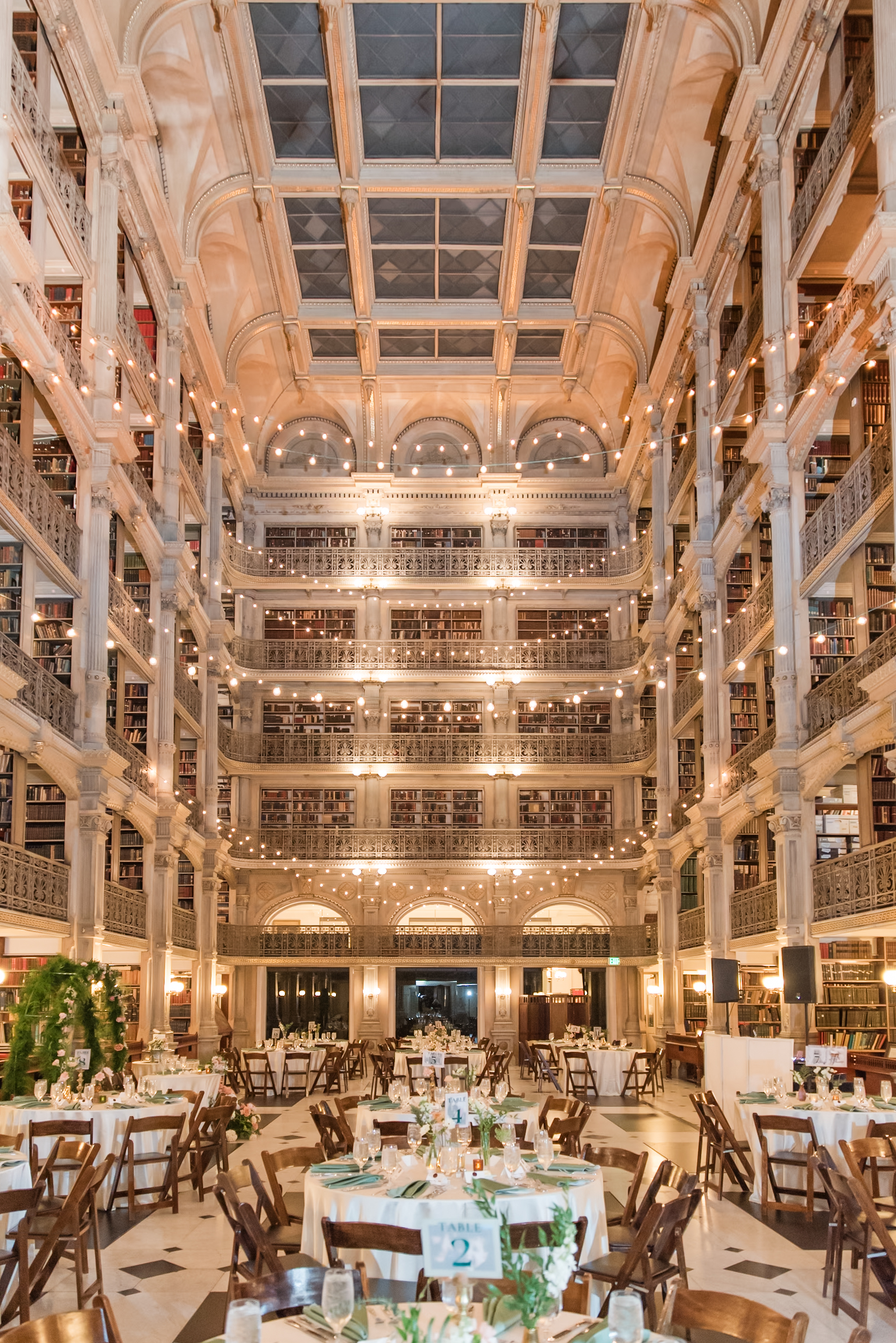 A wide view of the incredibly beautiful George Peabody Library Wedding venue set up with tables and market lights