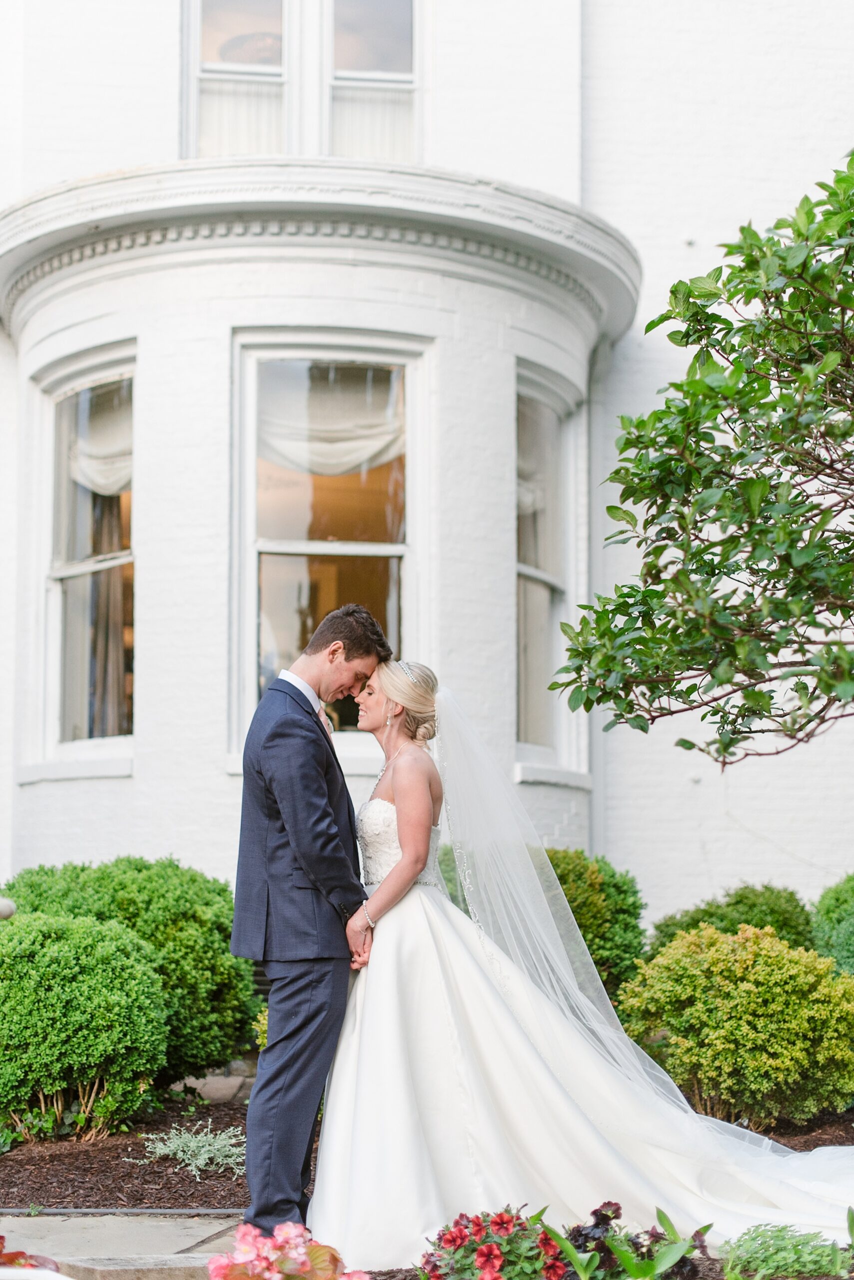 Newlyweds share a quiet moment touching foreheads in a garden