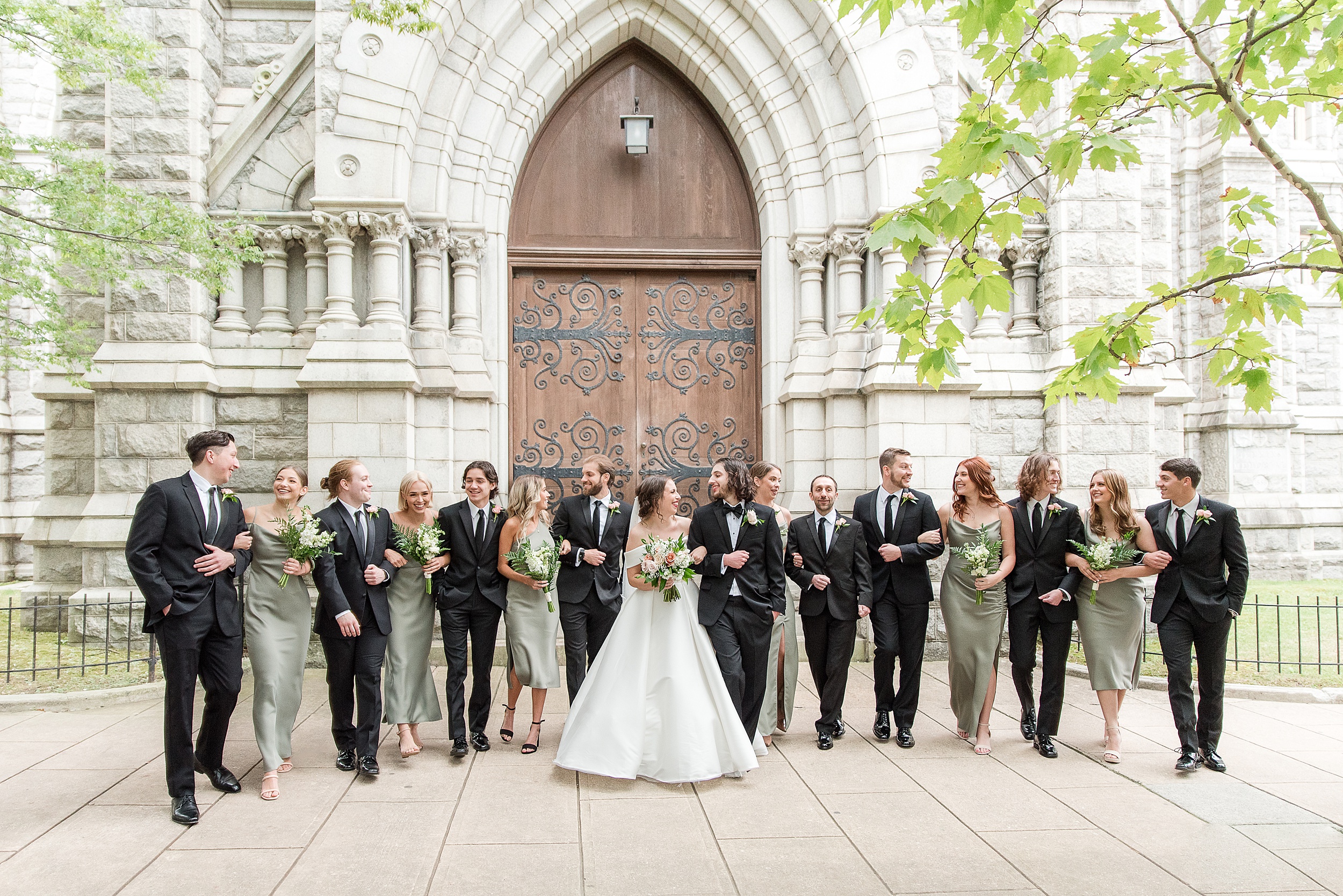 Newlyweds walk together with their large wedding party in front of an ornate Havre de Grace Wedding Venue