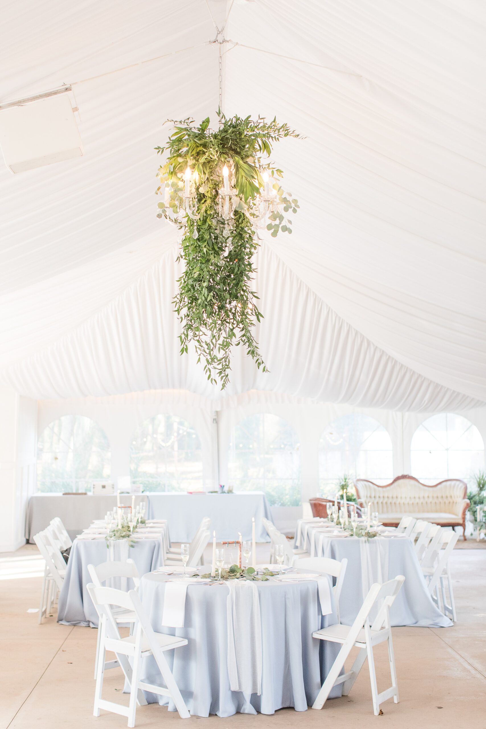 A look into a tent Historic Shady Lane Wedding reception with blue linen and a living chandelier