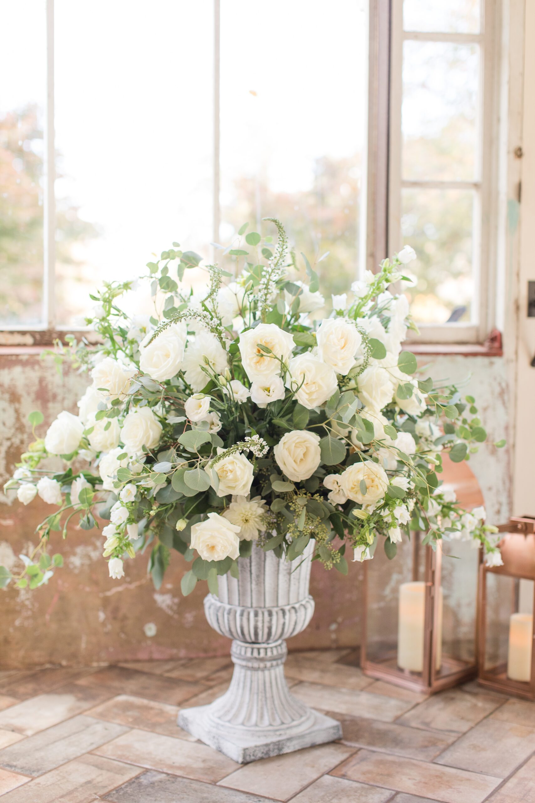 Details of a large floral arrangement in a tall vase with white roses