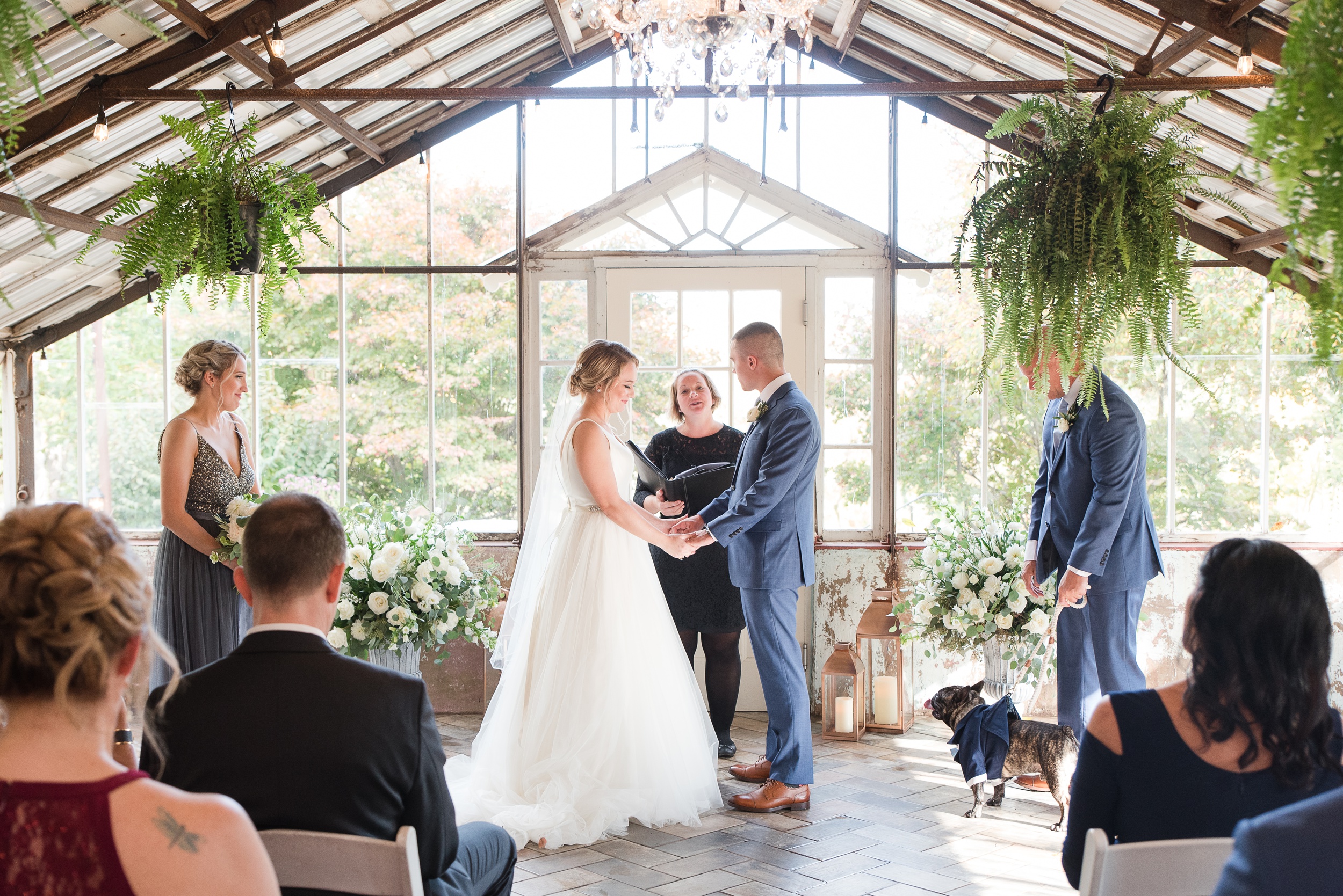 A bride and groom stand in their greenhouse Historic Shady Lane Wedding ceremony holding hands