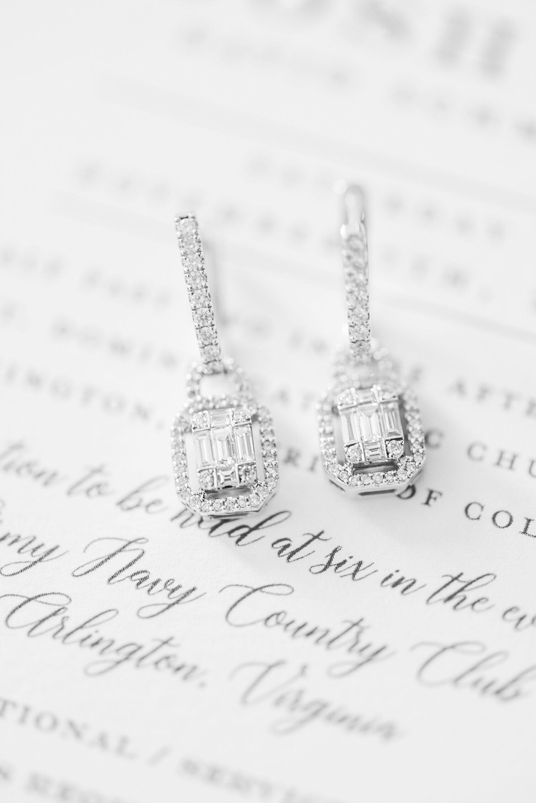 Details of diamond earrings sitting on a wedding invitation