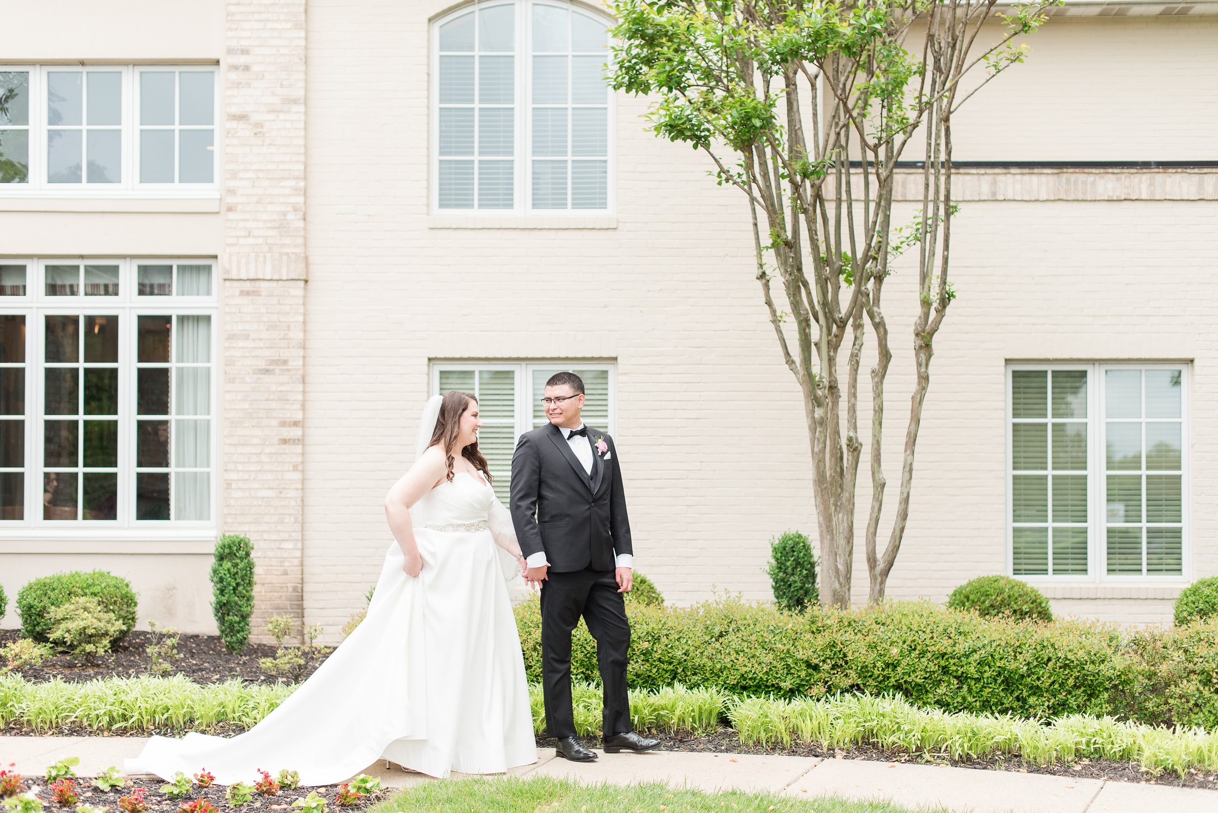 Newlyweds giggle while walking down the sidewalk and holding hands