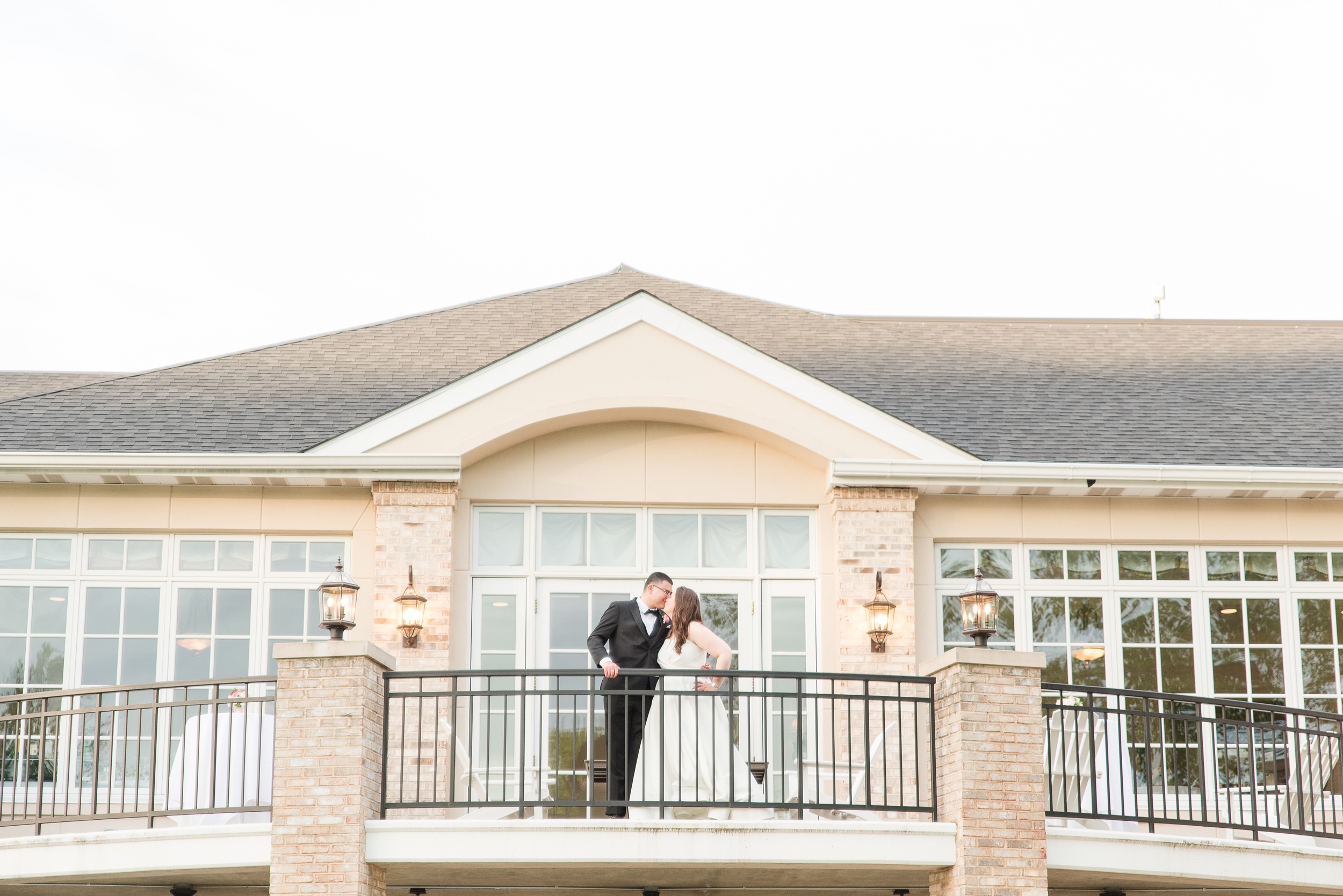 Newlyweds kiss on a balcony of the Manor Country Club Wedding venue