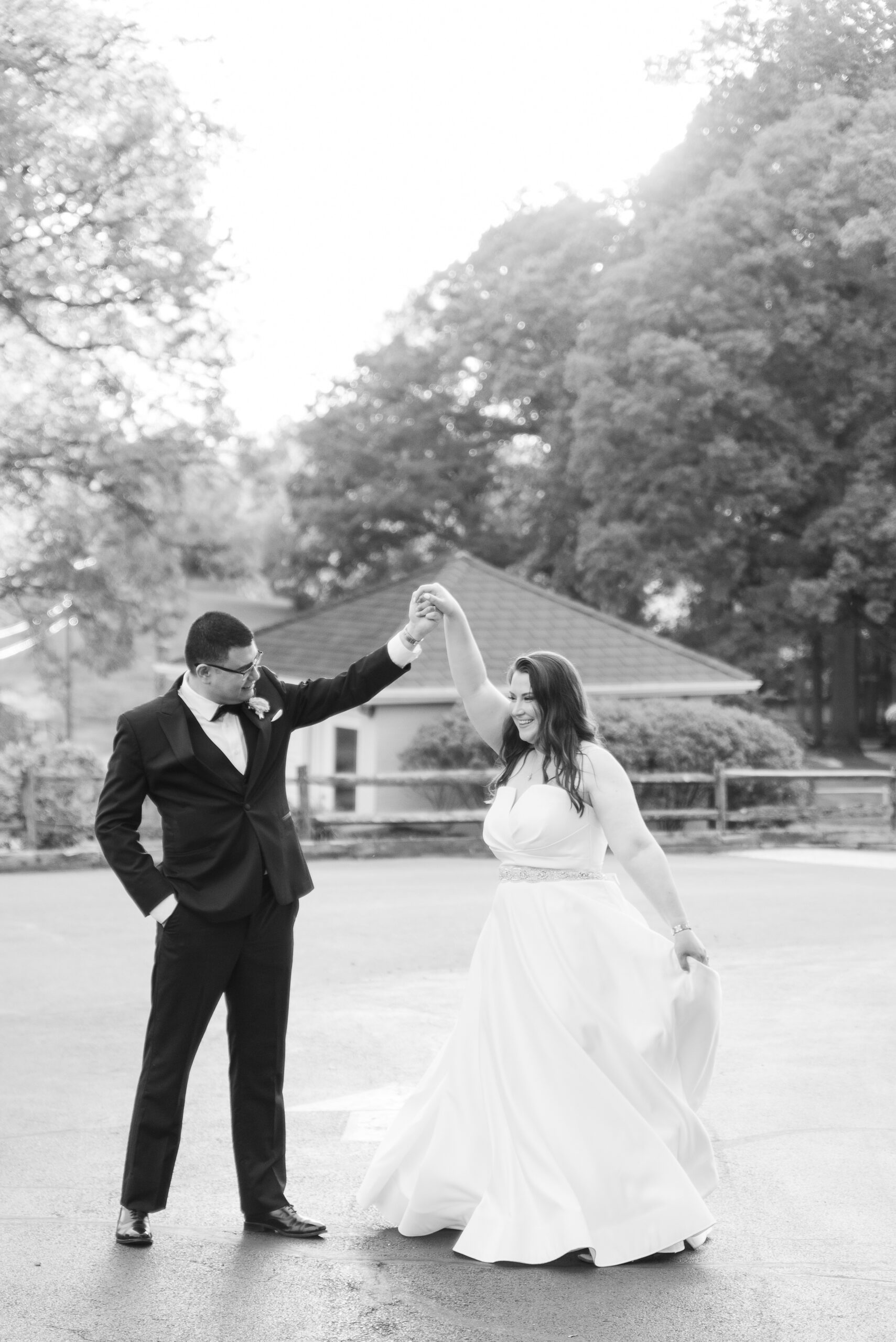 A groom spins his bride as they dance outside at the Manor Country Club Wedding venue