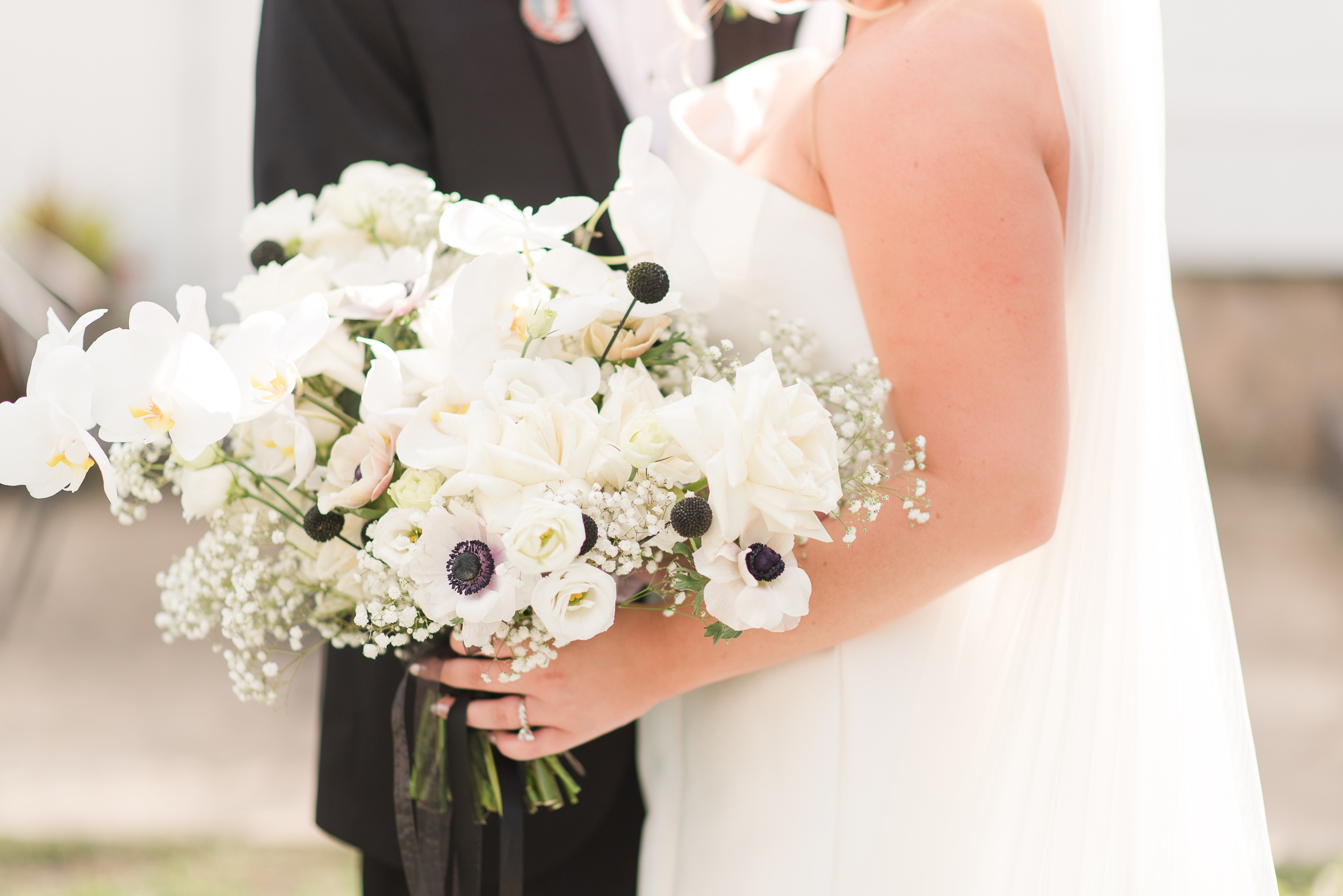 Details of a brides white and black bouquet in her hand