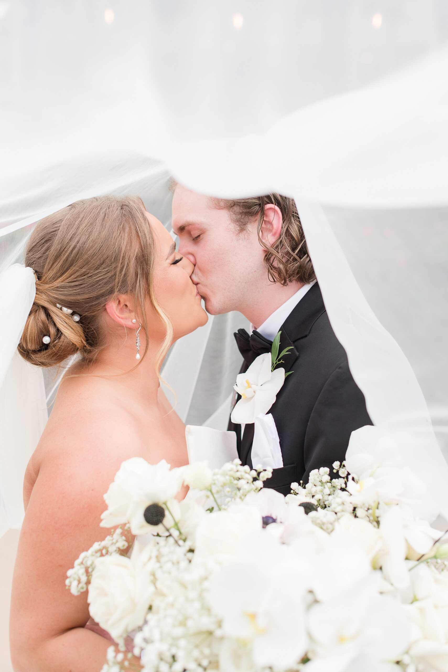 Newlyweds kiss while hiding under a large veil