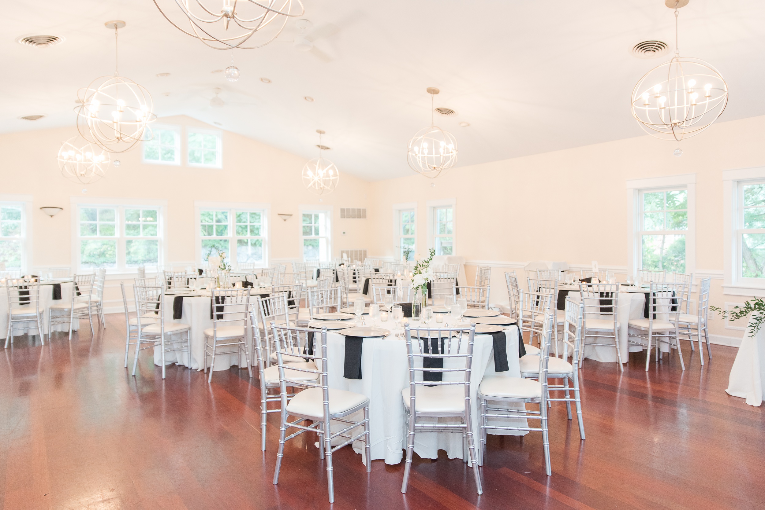 A view of the Milton Ridge Wedding reception room with modern chandeliers and black napkins on tables