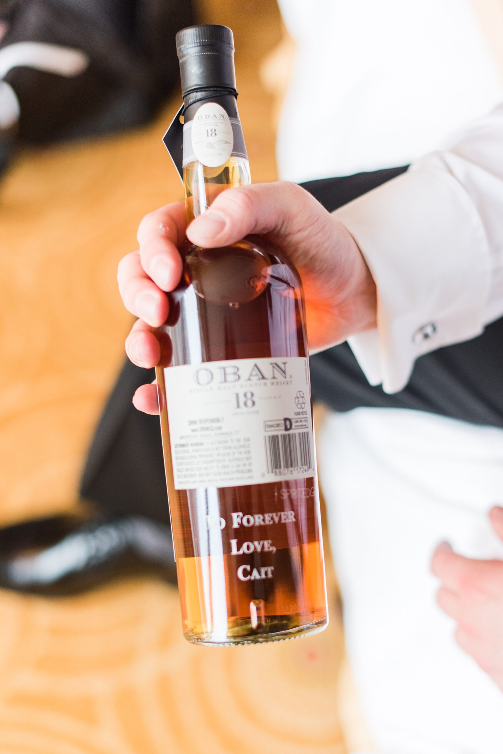 A groom holds a customized bottle of whiskey gifted from his bride for their Mt. Washington Dye House Wedding