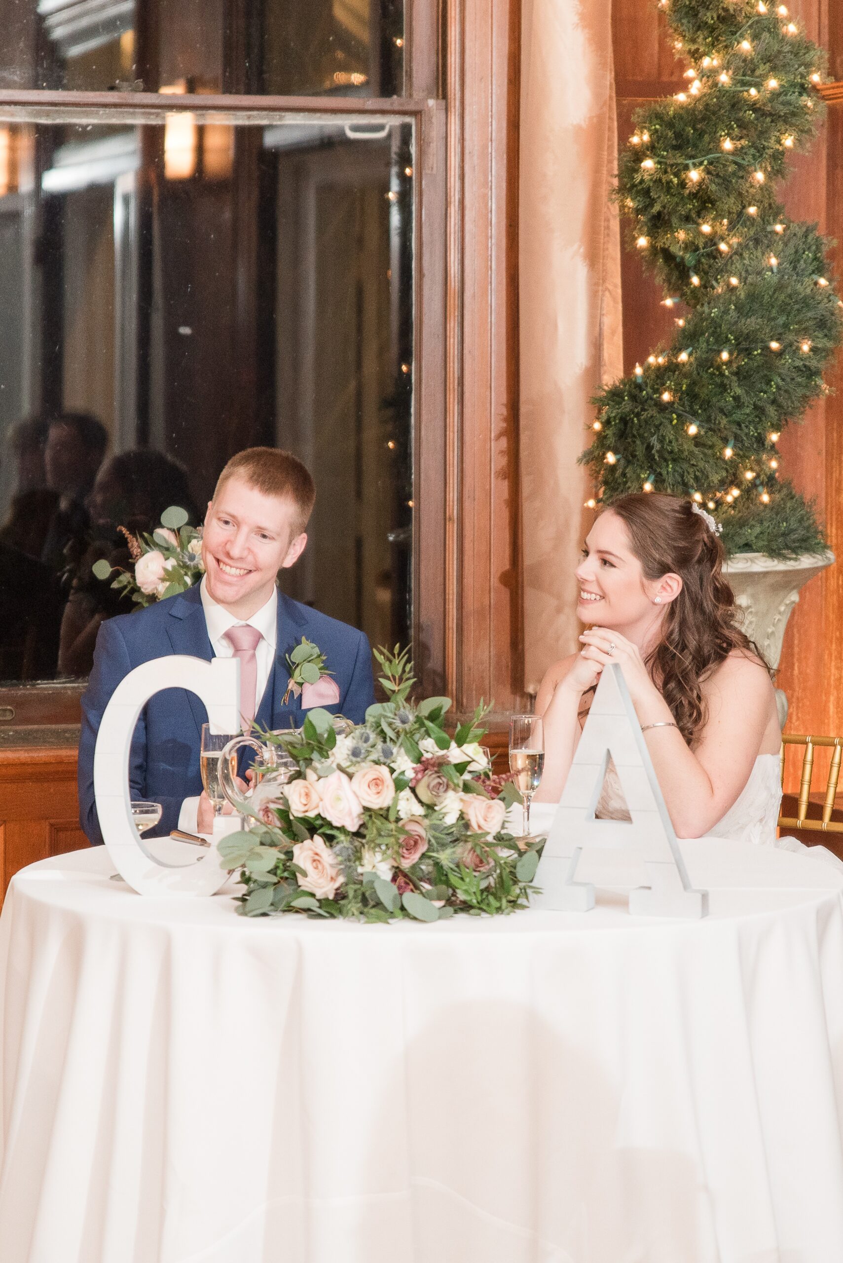 Newlyweds smile big while sitting at their head table