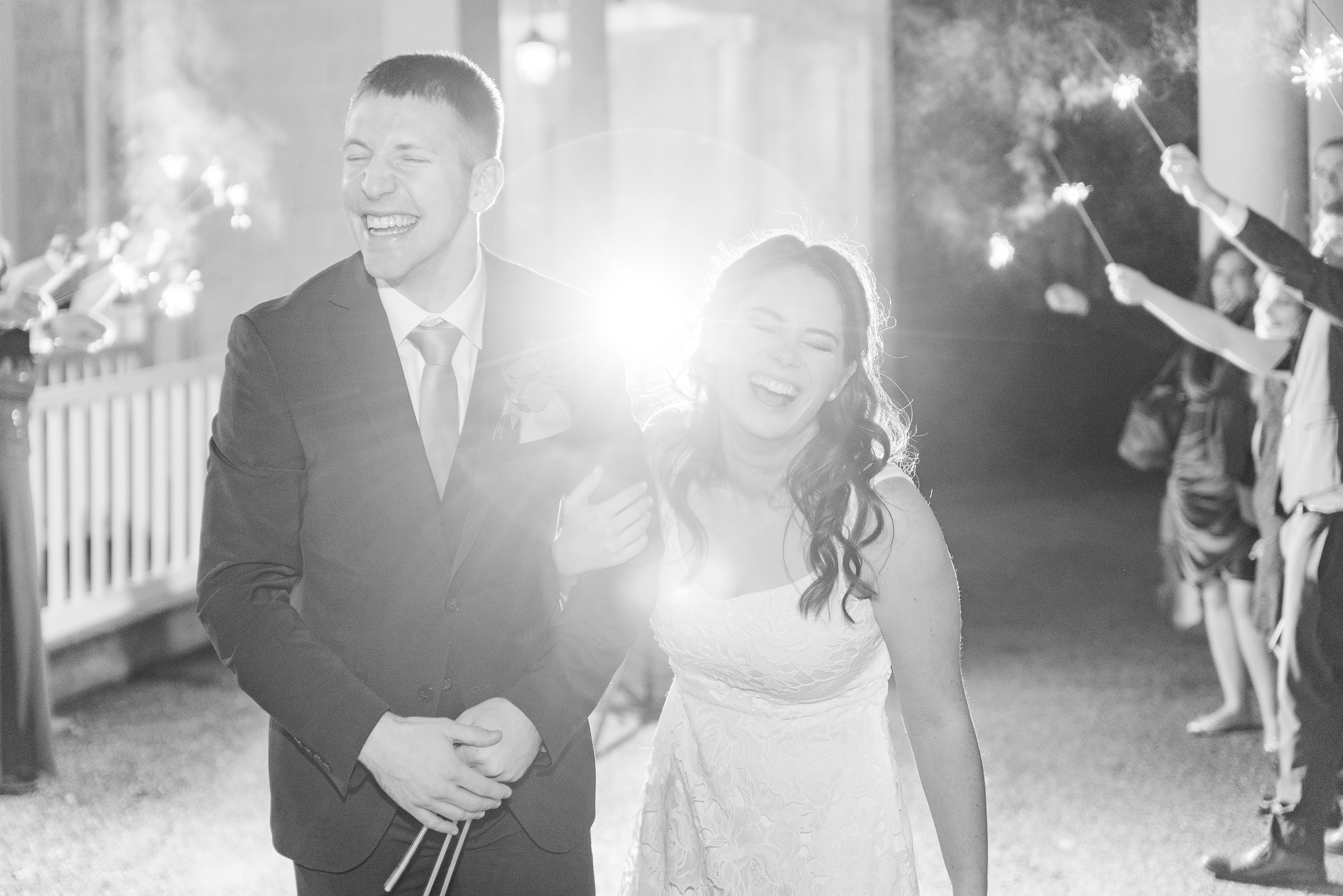 Newlyweds laugh while walking through a sparkler exit at their Overhills Mansion Wedding