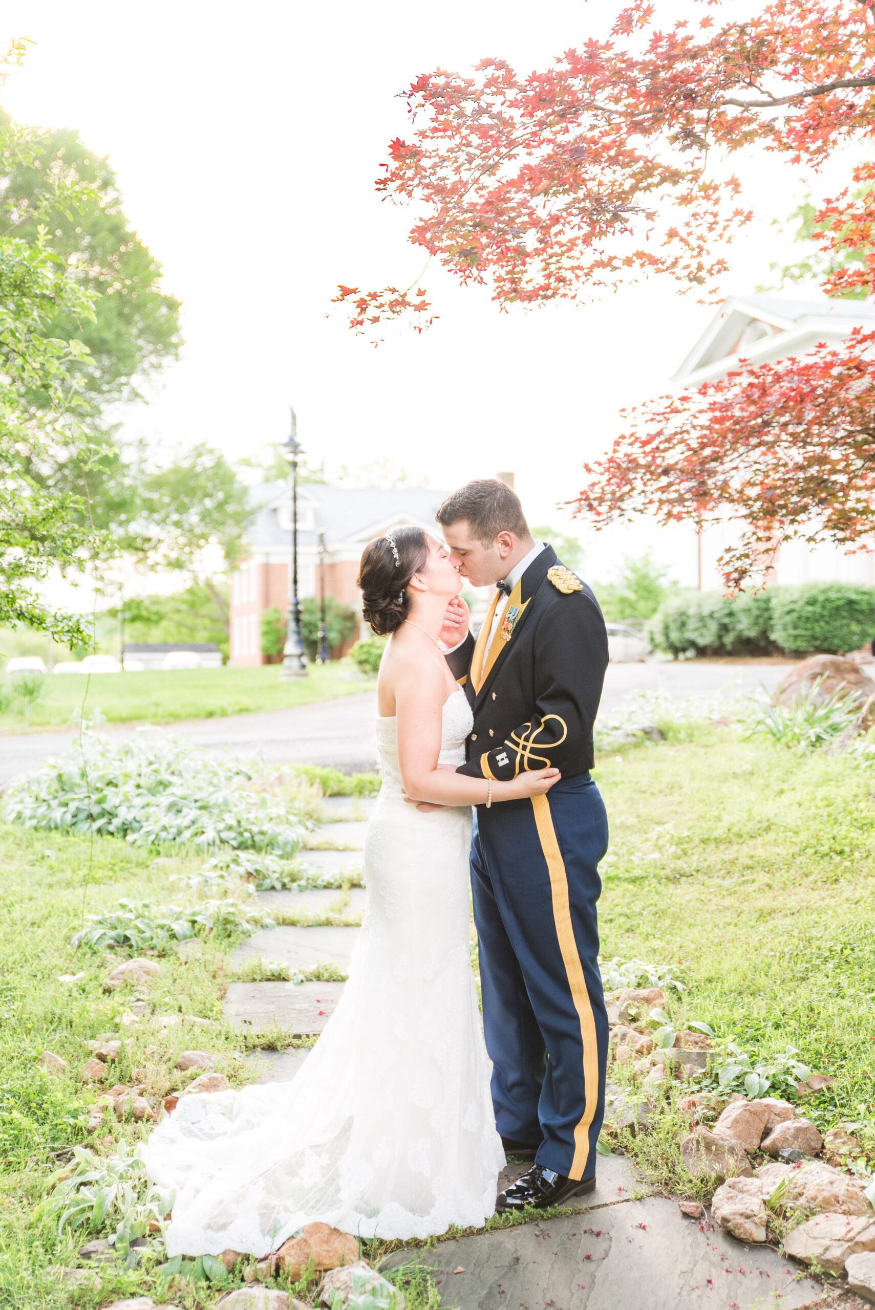 Newlyweds kiss in a small stone path under a red tree at their Raspberry Plain Manor Wedding