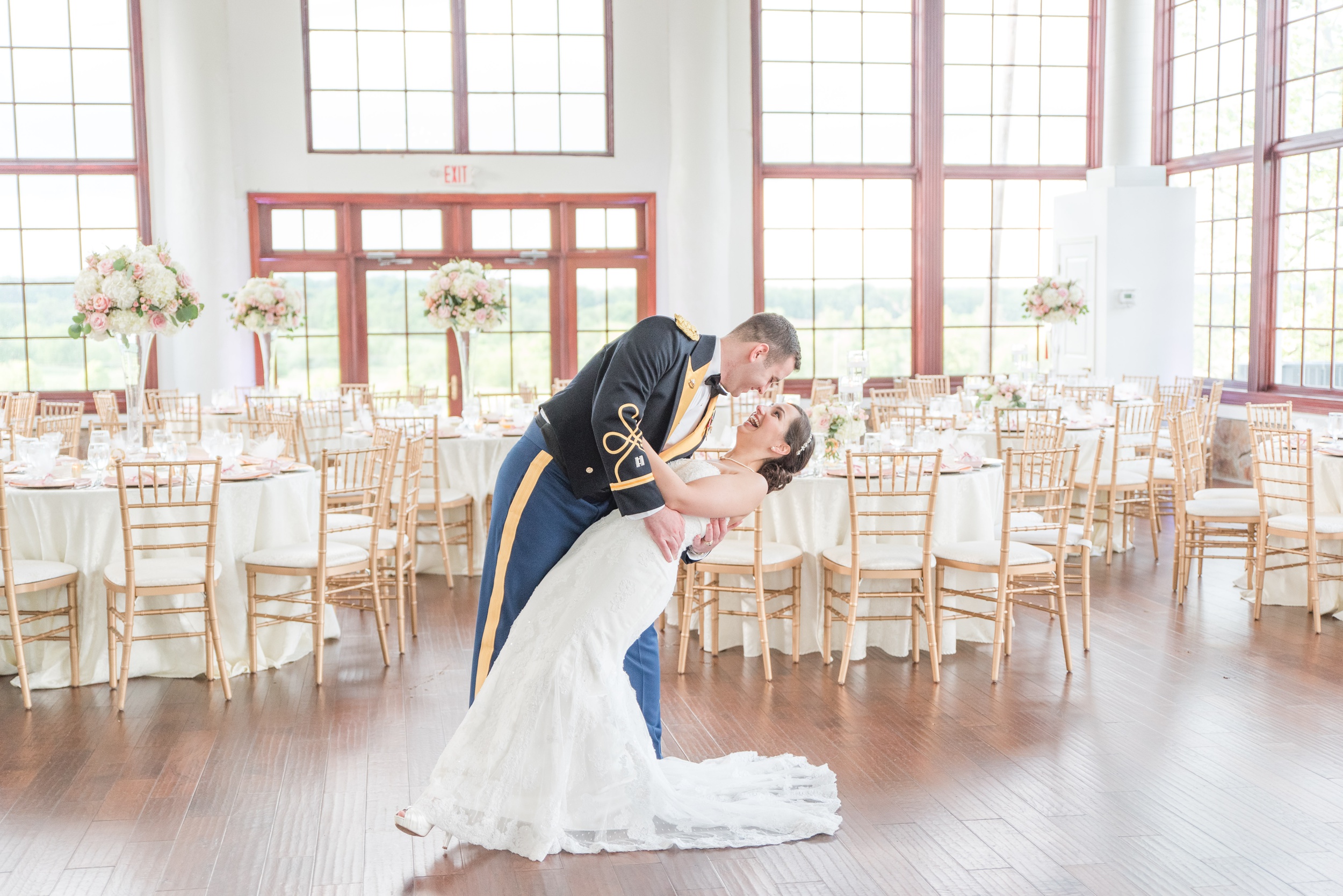 A groom dips his laughing bride in their empty Raspberry Plain Manor Wedding reception room