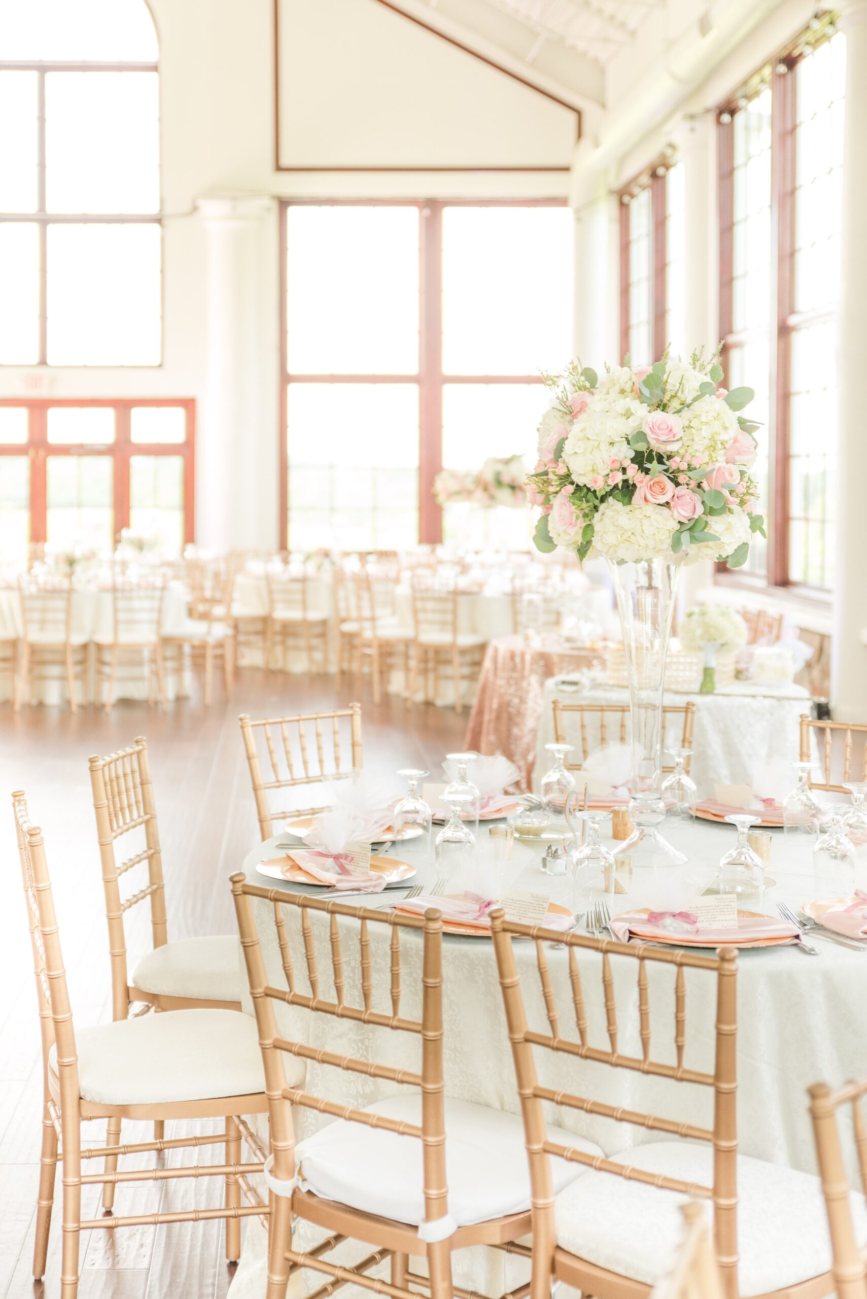 Details of a wedding reception table with wooden chairs and white linen