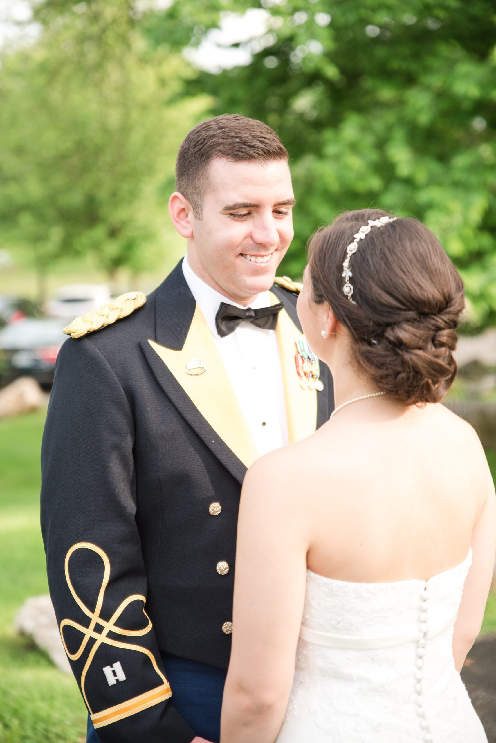 A groom in military uniform smiles while seeing his bride at their Raspberry Plain Manor Wedding