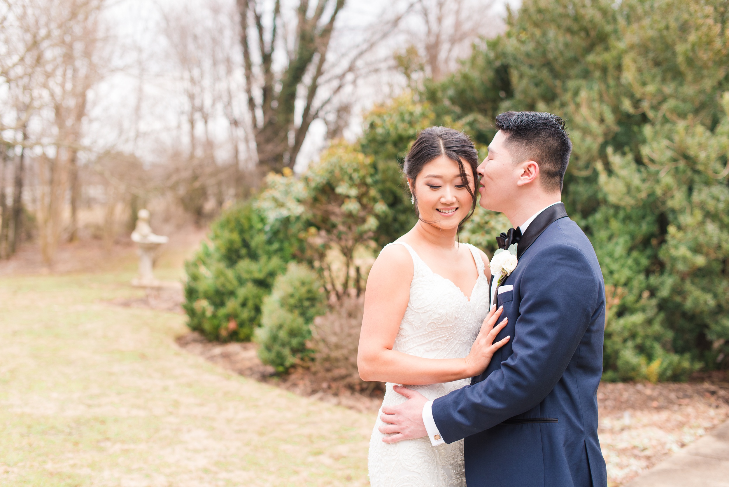 A groom whispers in his bride's ear as they explore a garden