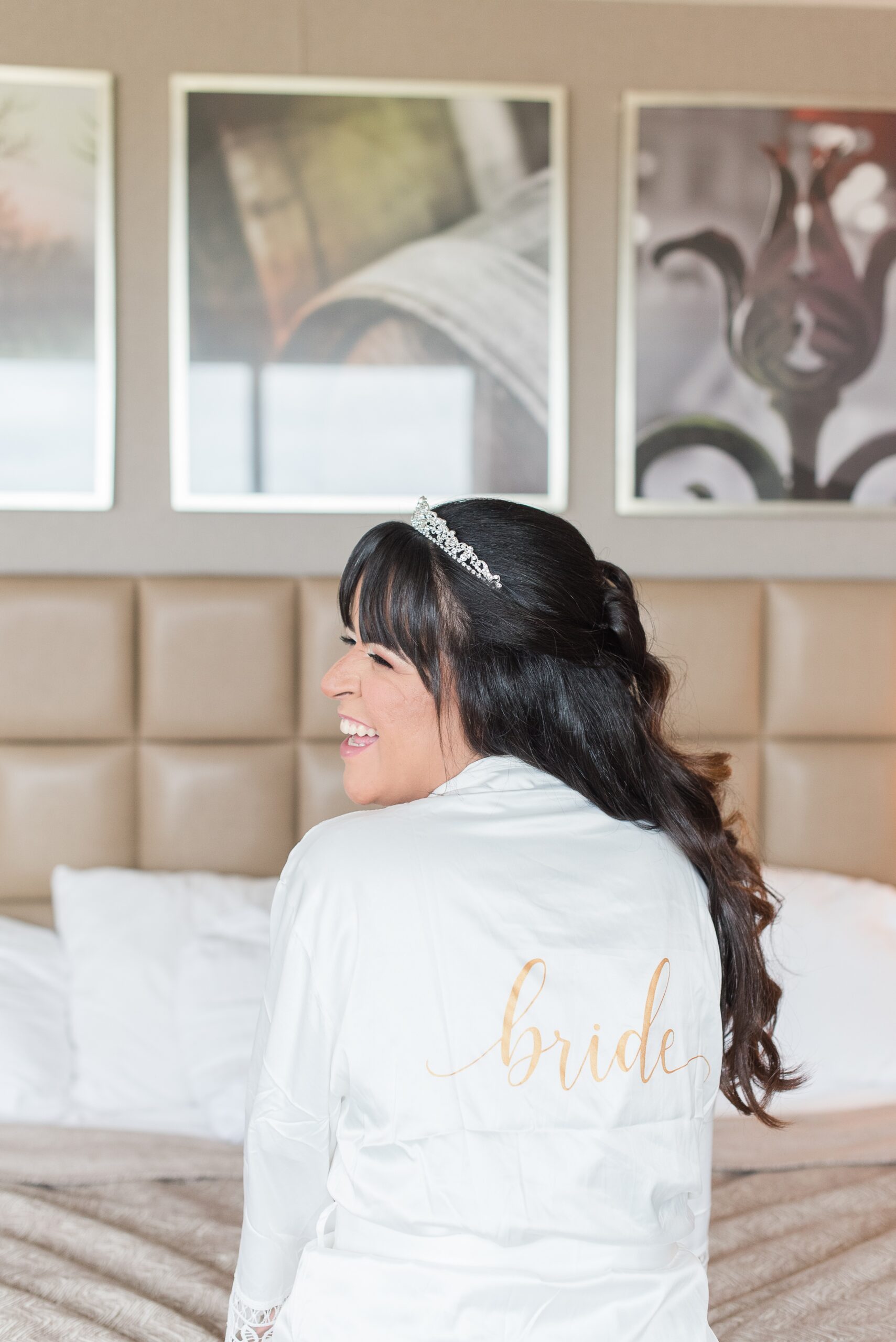 A bride laughs over her shoulder in her custom white pajamas robe