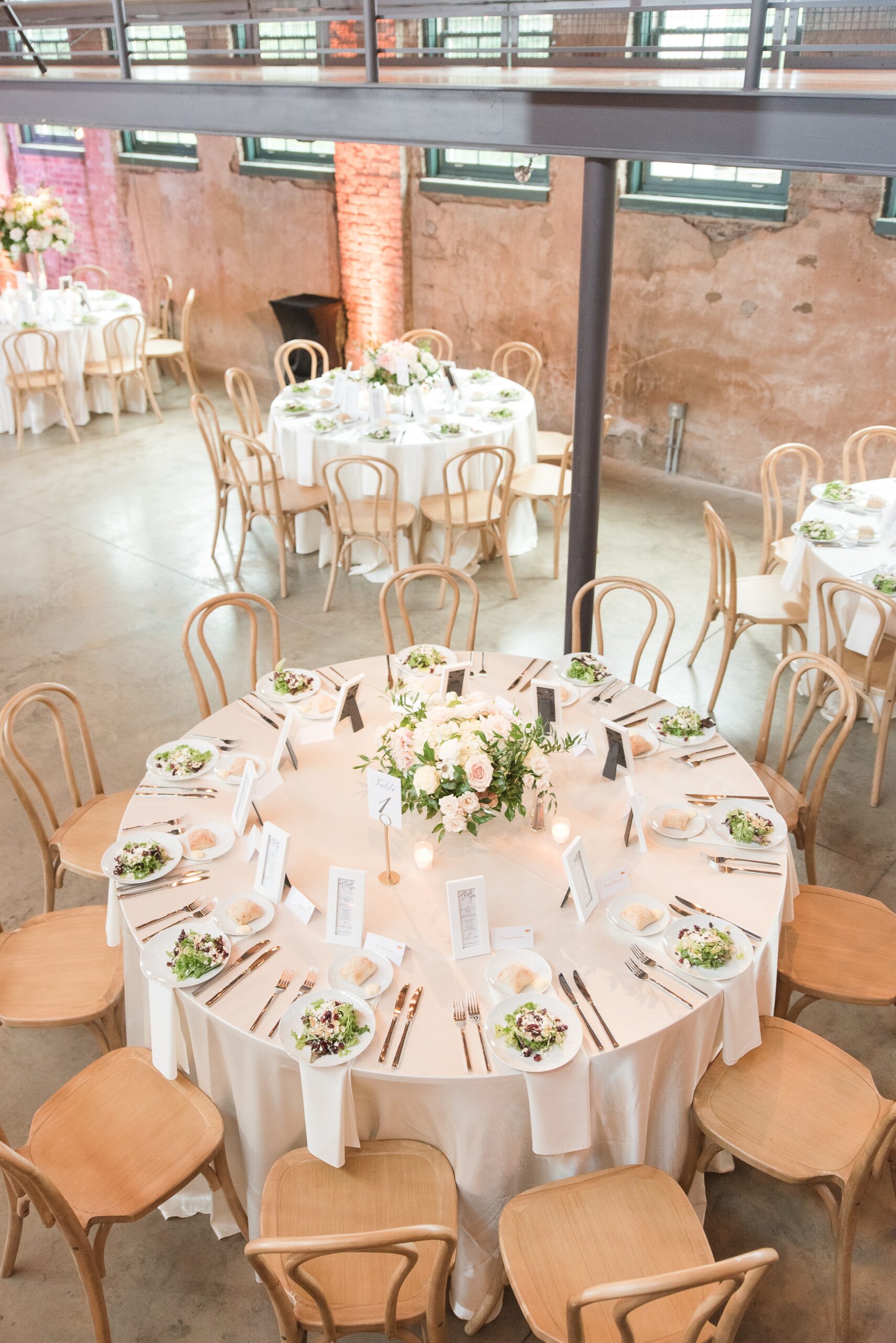 A look down from the balcony to a round reception table with wooden chairs at The Winslow Baltimore