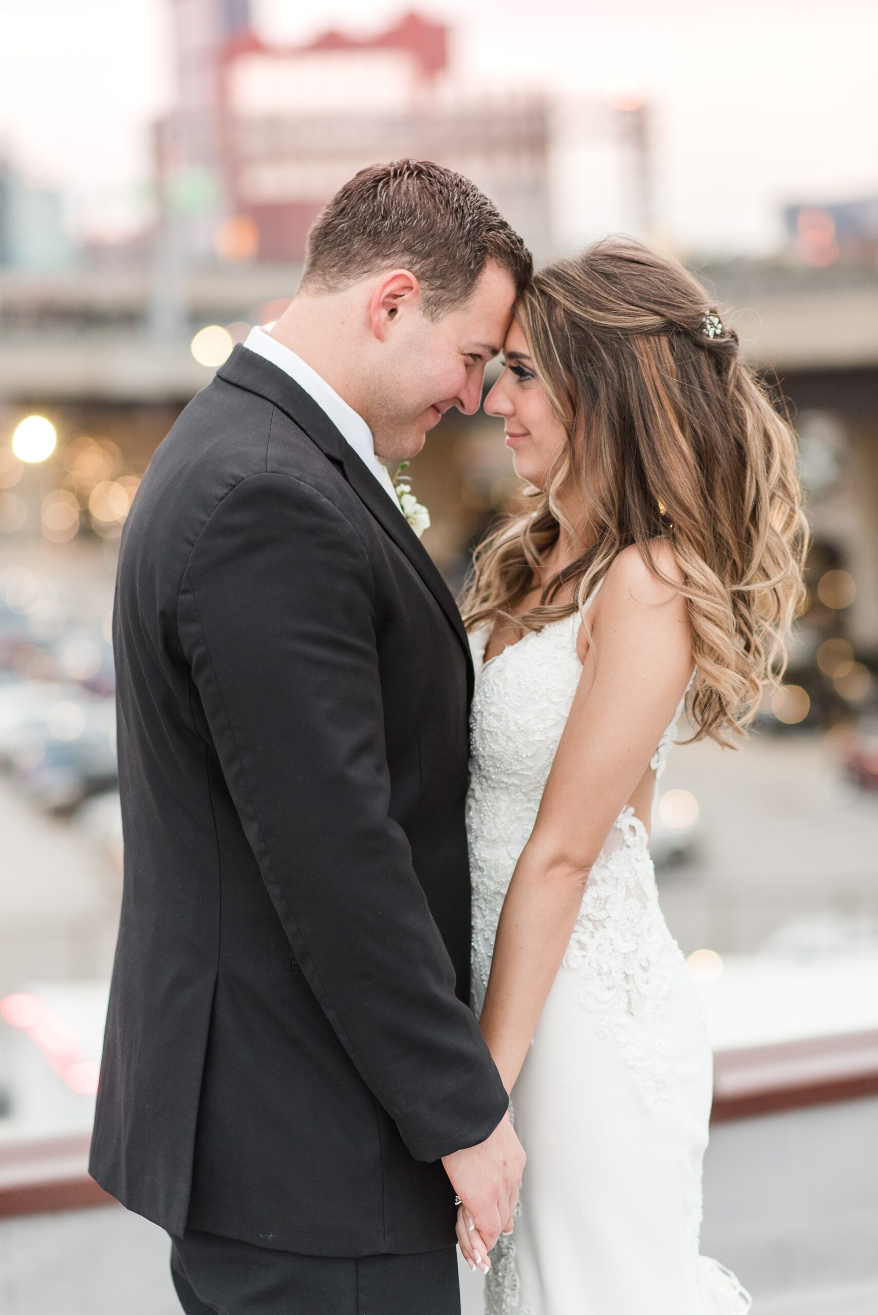 Newlyweds touch foreheads while standing on a balcony at their wedding at The Winslow Baltimore