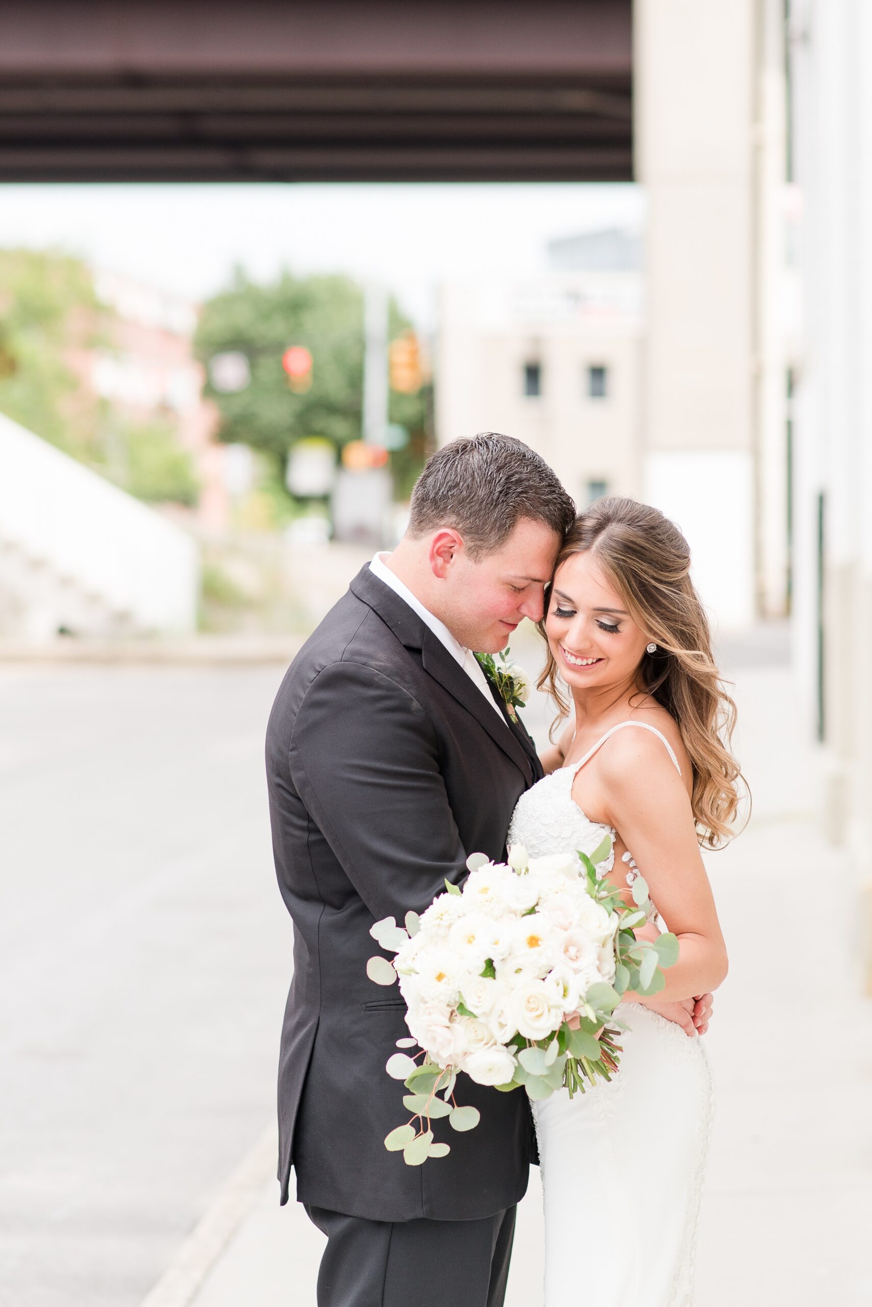 Newlyweds snuggle while standing in an alley at The Winslow Baltimore