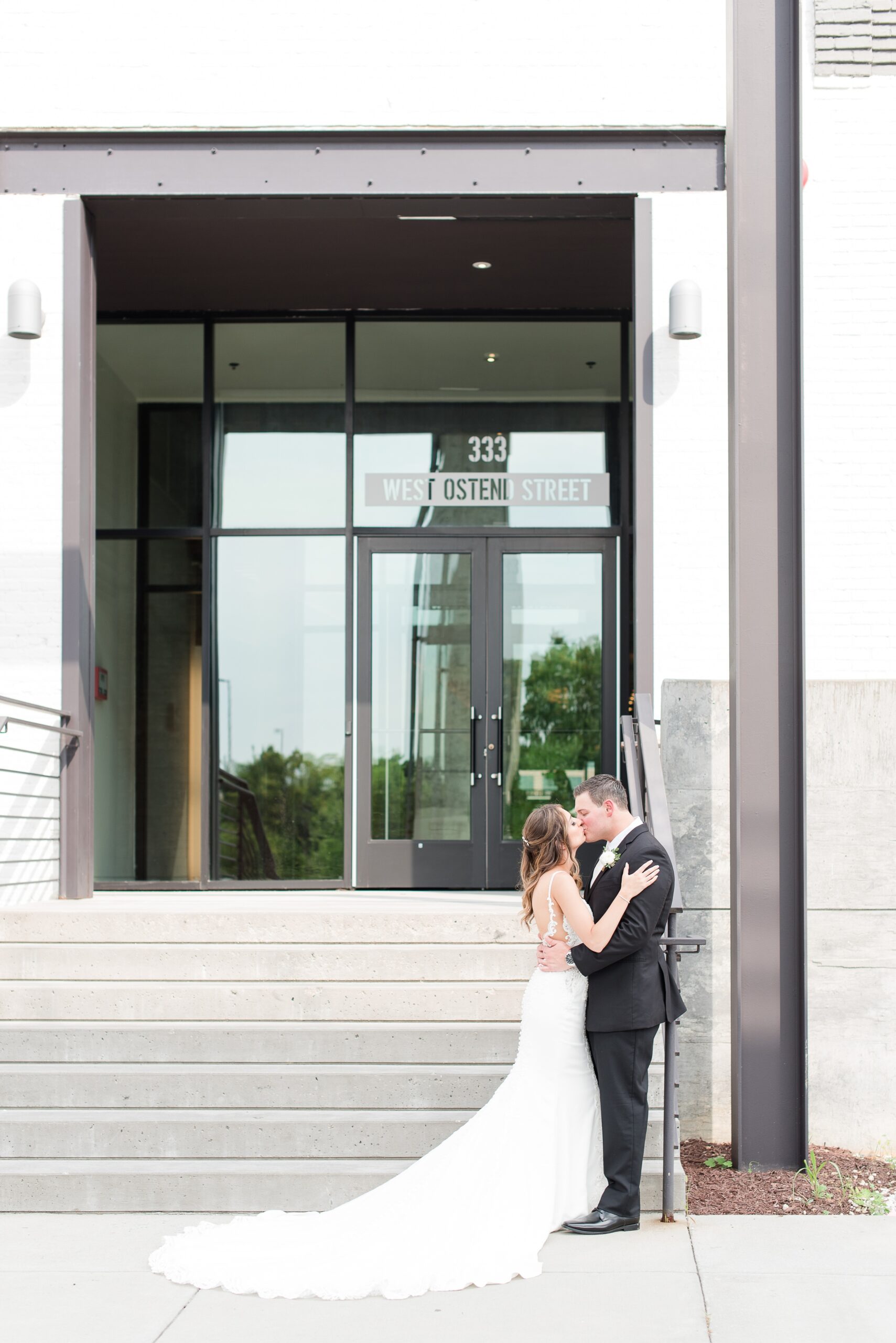 Newlyweds kiss while leaning on a stair railing at their wedding