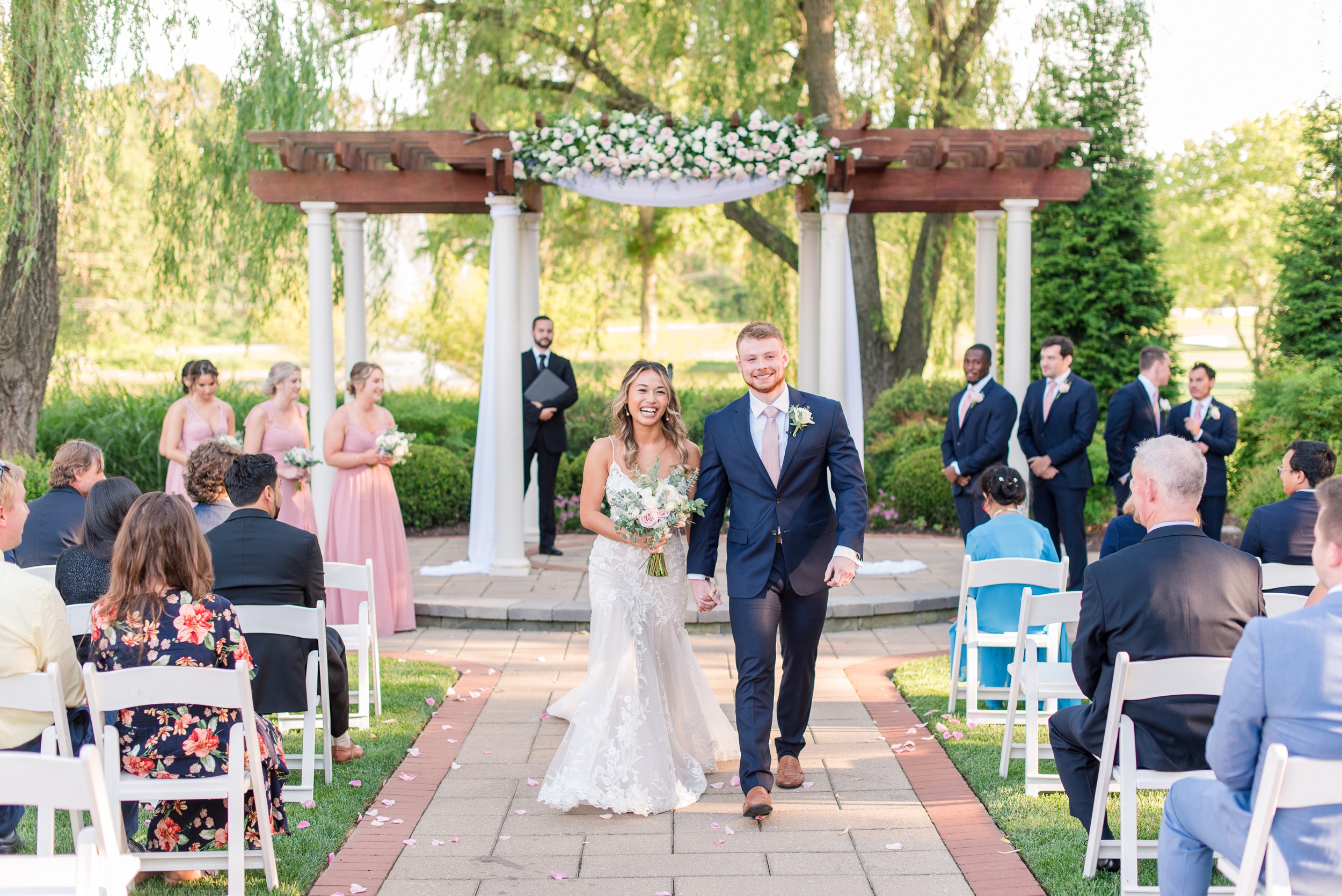 Newlyweds happily walk up the aisle holding hands to end their outdoor Turf Valley Resort Wedding under a pergola