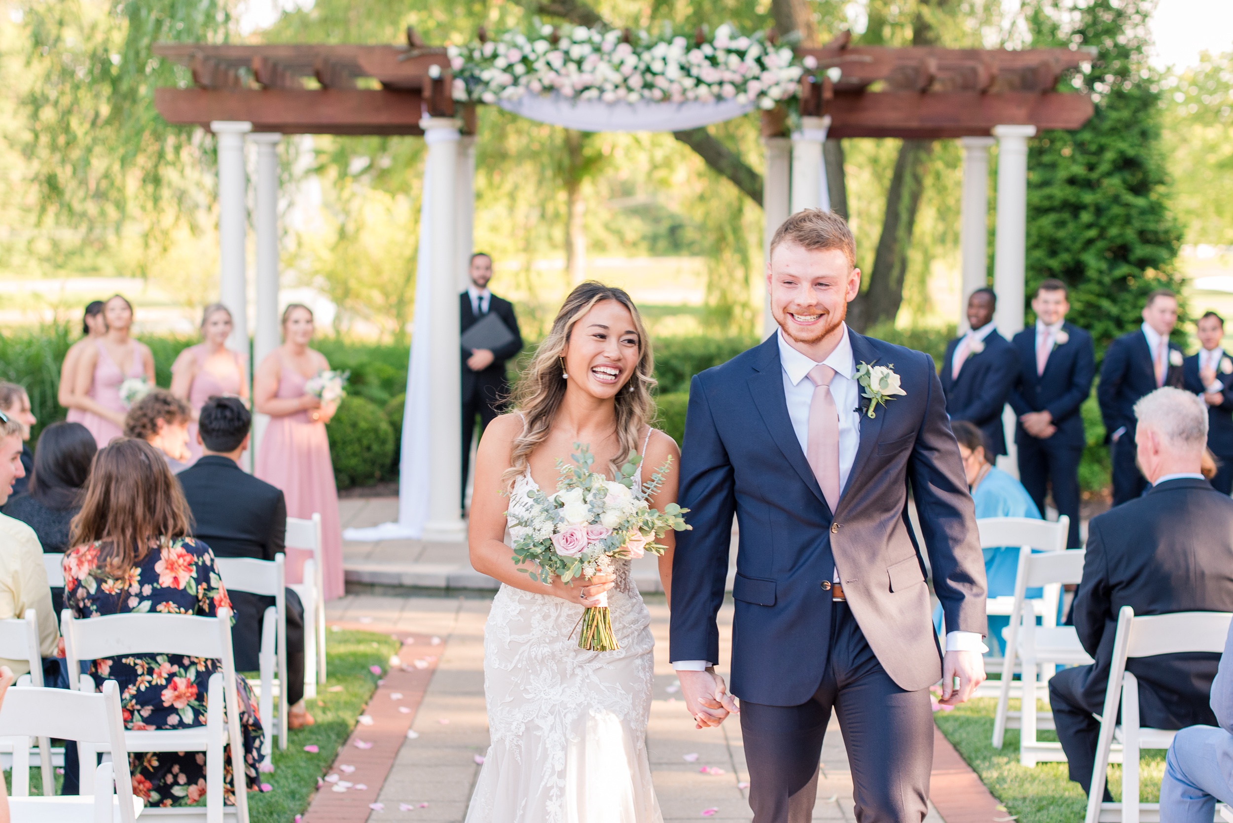 Newlyweds laugh and smile while walking up the aisle at their outdoor Turf Valley Resort Wedding ceremony