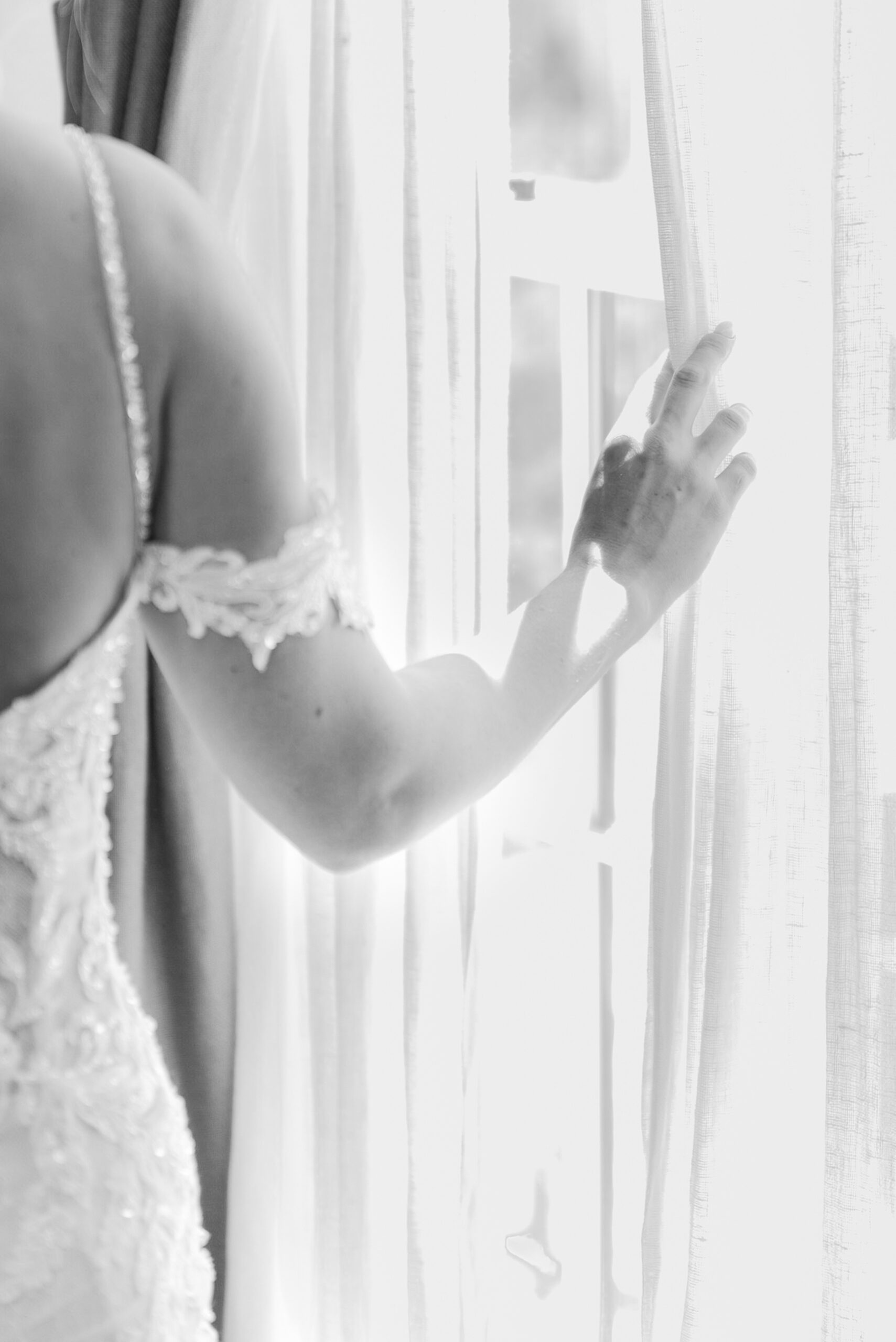 Details of a bride pulling a window curtain back to peek out while in her lace dress at her Vandiver Inn Wedding