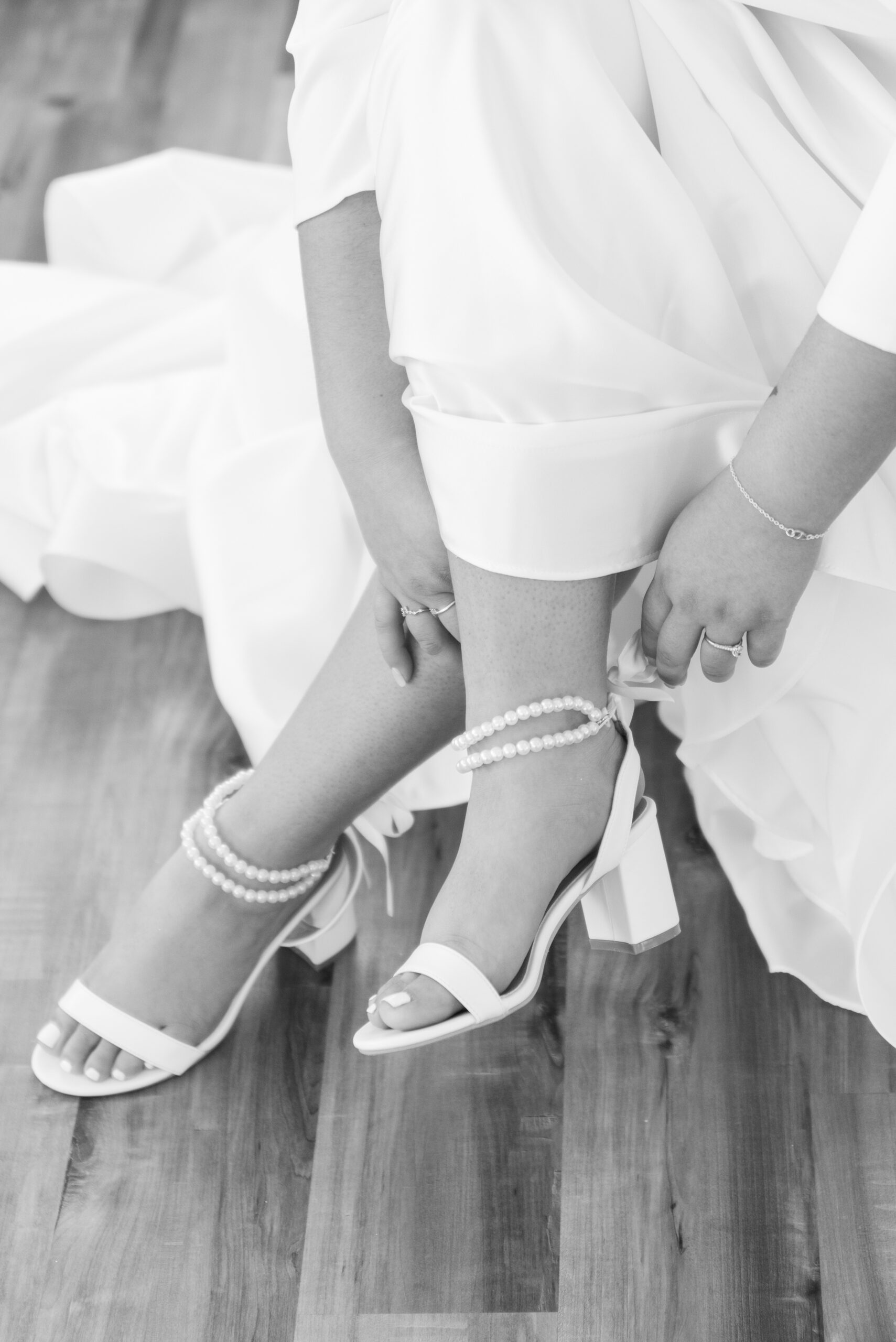 Details of a bride putting on her pearl strap shoes