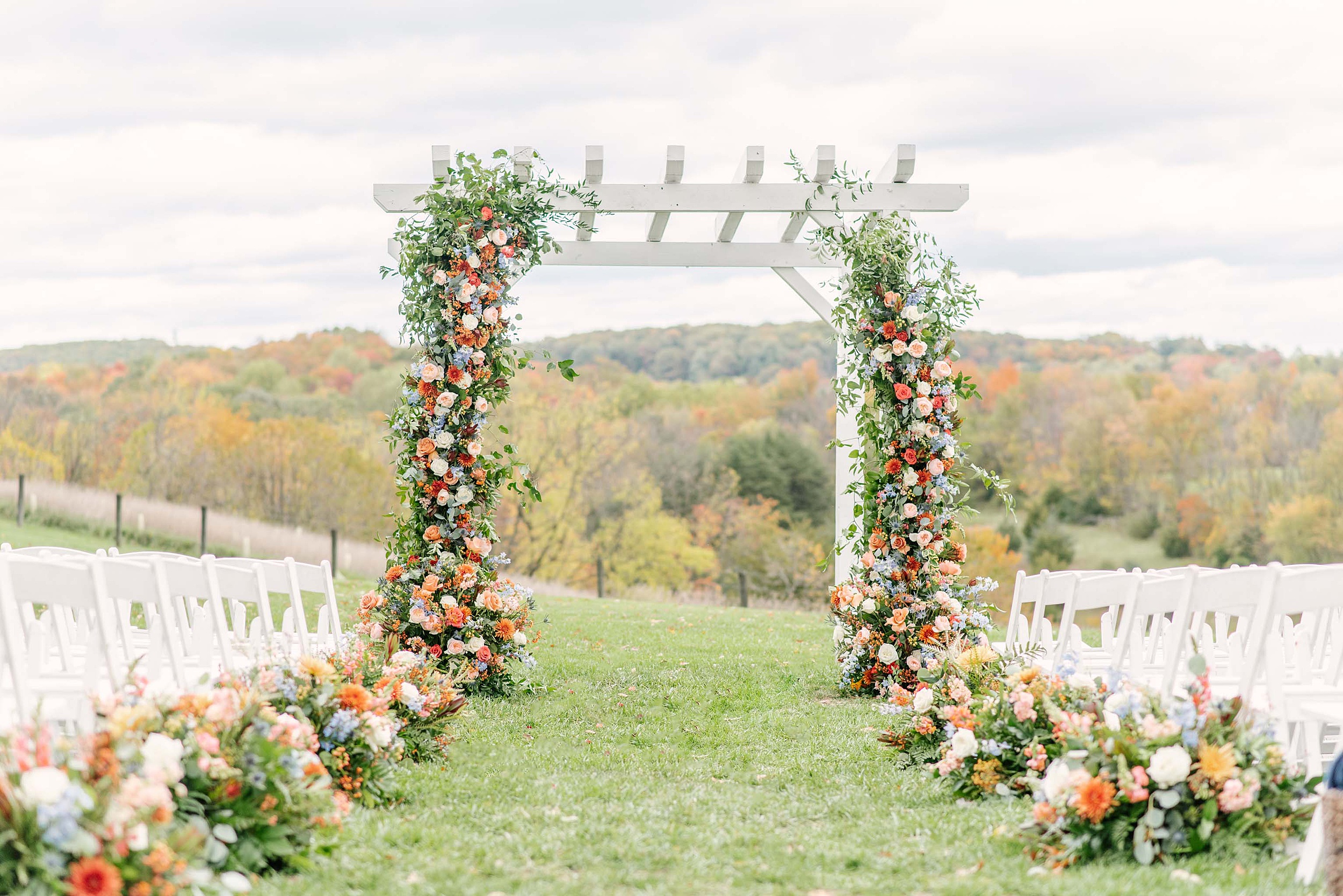 A view of a pergola arch set up with colorful florals for an outdoor wedding ceremony at one of the Wedding Venues Leesburg, VA