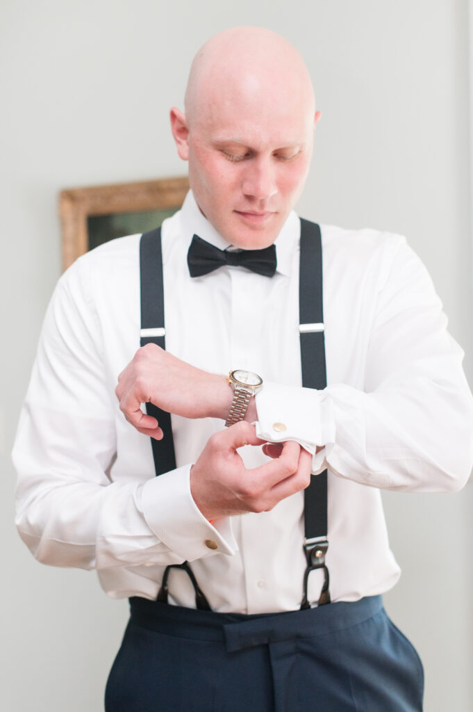 groom tied cufflinks on wedding day