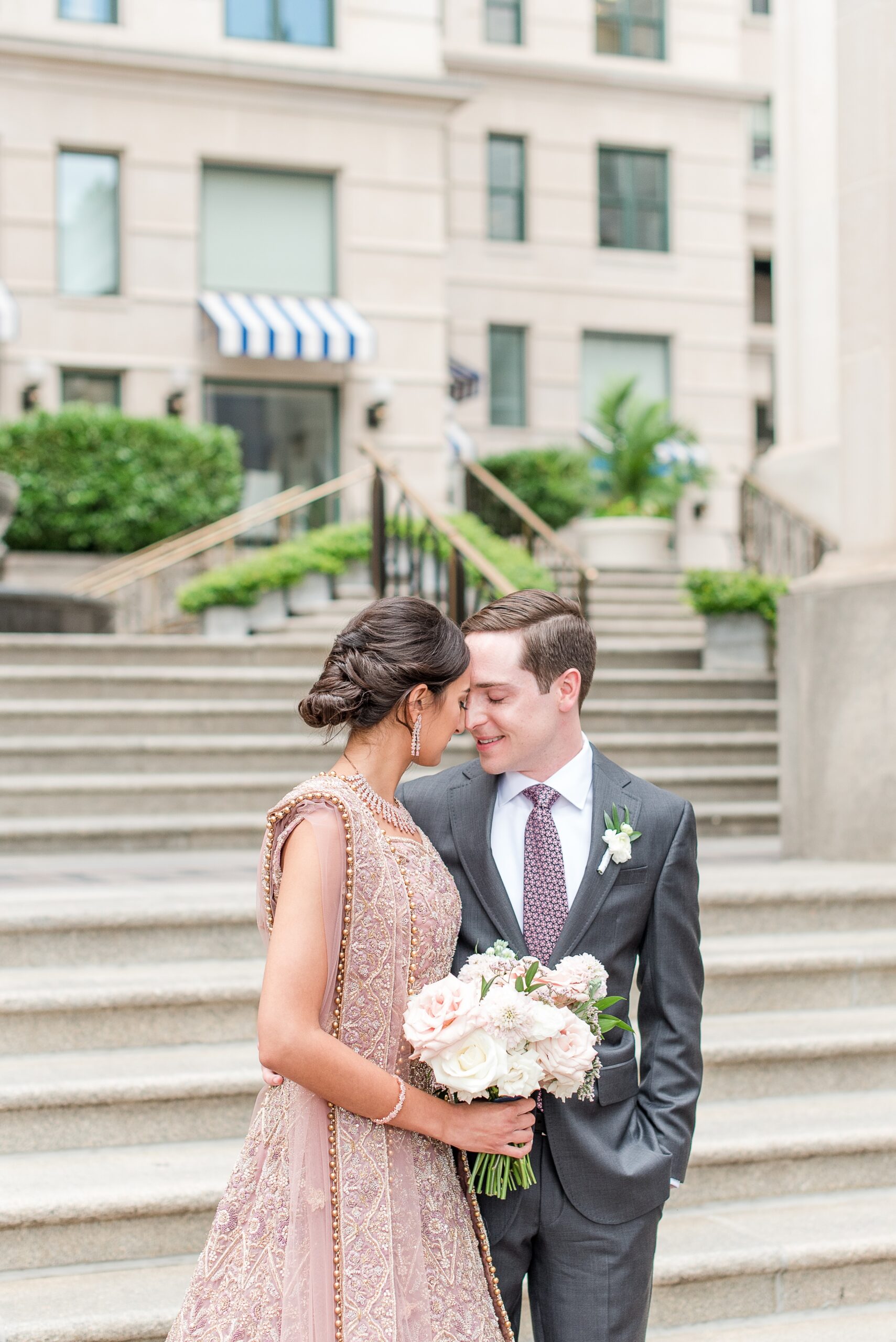 Newlyweds nuzzle noses while standing by the stairs at the DAR Wedding venue