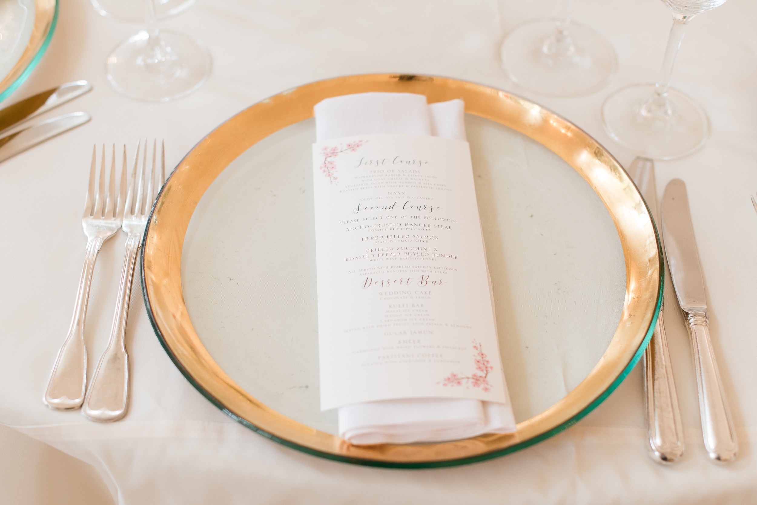 Details of a table setting with a gold rimmed charger and menu