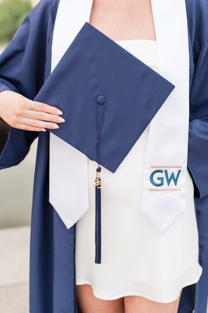 close up of GW graduate holding cap and wearing gw stole