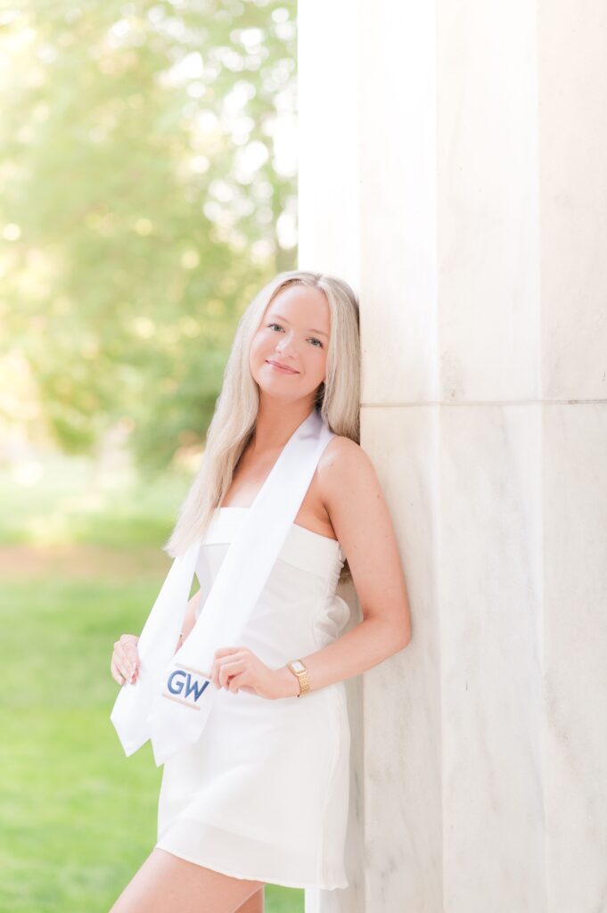 GW graduate leqaning on a column